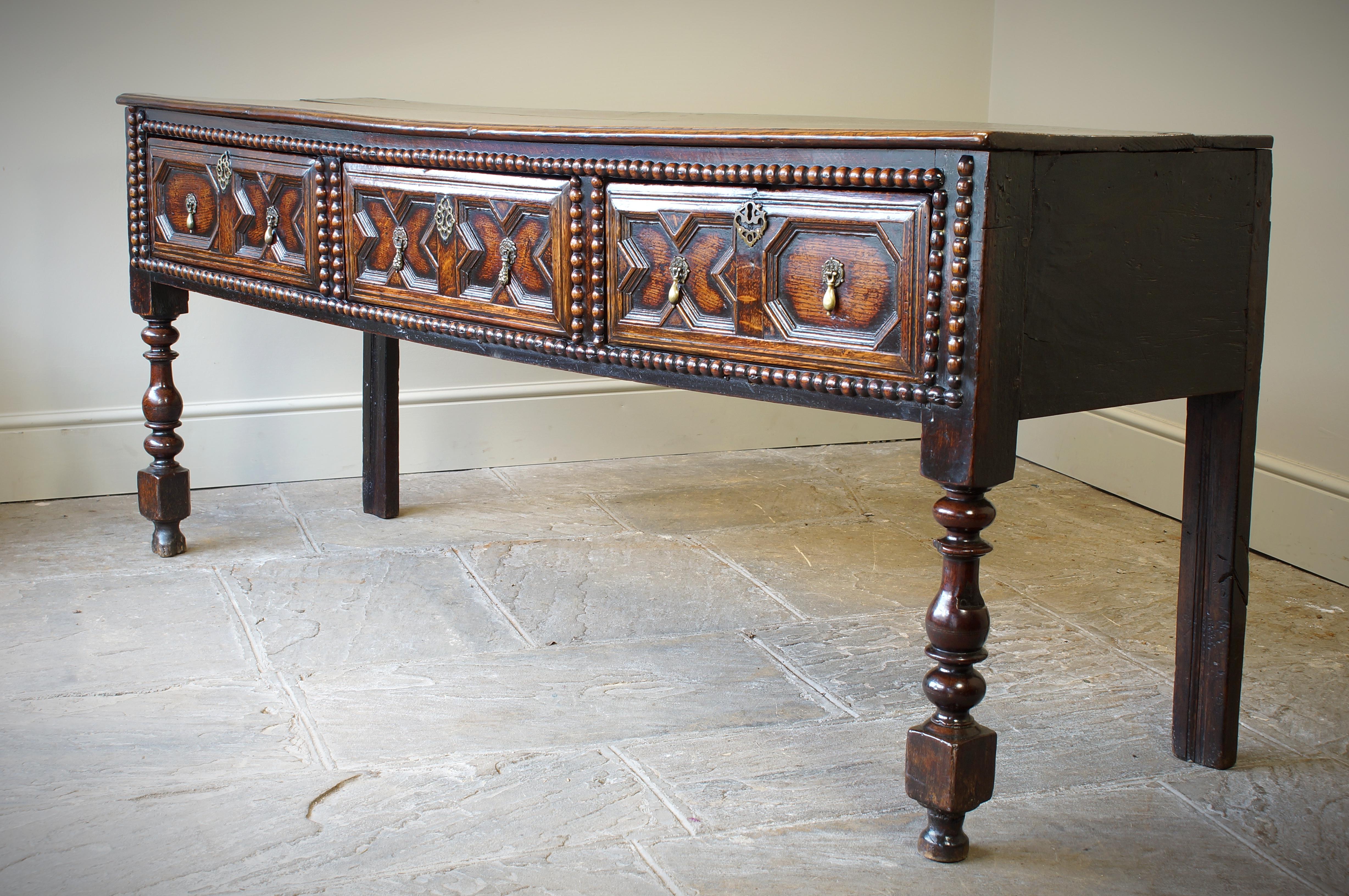 An excellent example of a moulded turned leg dresser from the Charles II period.
Having a two piece top above three geometrically moulded drawers, the framing is decorated with applied split bobbin turnings and standing on boldly turned front