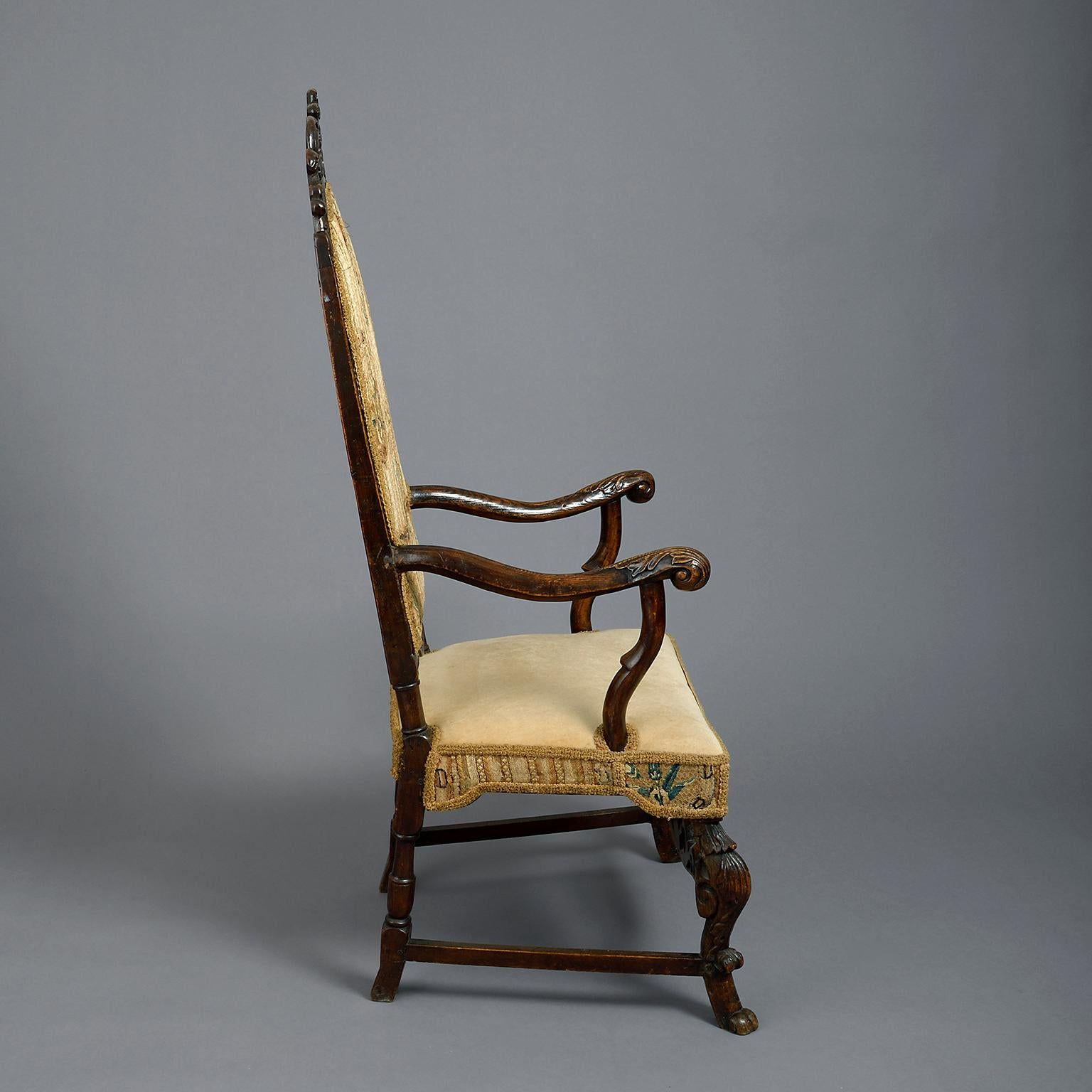 Niederländischer Sessel aus dem 17. Jahrhundert, hohe gepolsterte Rückenlehne mit Lambrequin- und Scrollkamm, mit nach außen gebogenen Armen, gepolsterter Sitzfläche und Cabriole-Beinen, die durch eine ebenfalls geschnitzte Bahre verbunden sind;