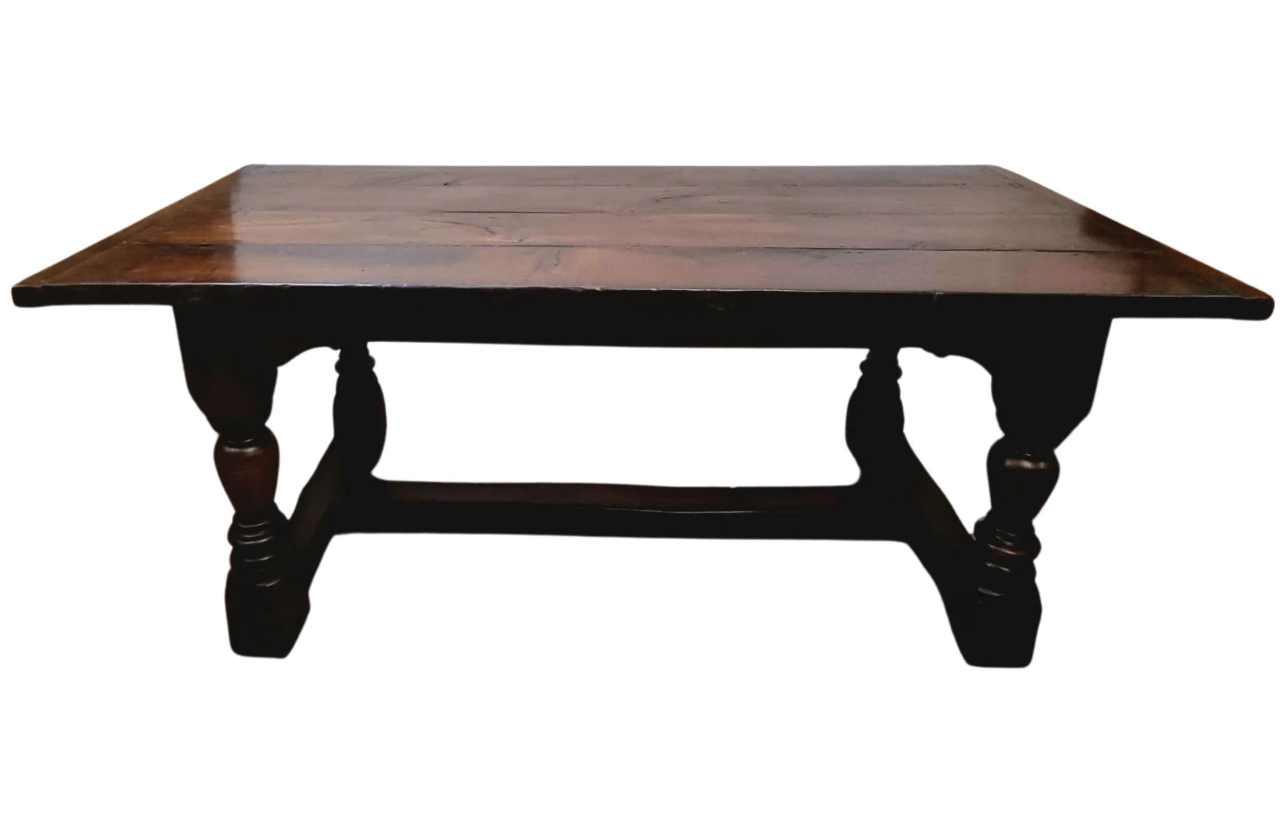 A 17th-century Oak Charles II Refectory table, dating from 1660-1685, comfortably seats six people. It features turned legs with side and centre stretchers and a solid four-plank oak top. The table exhibits a wonderful deep, rich patina that has