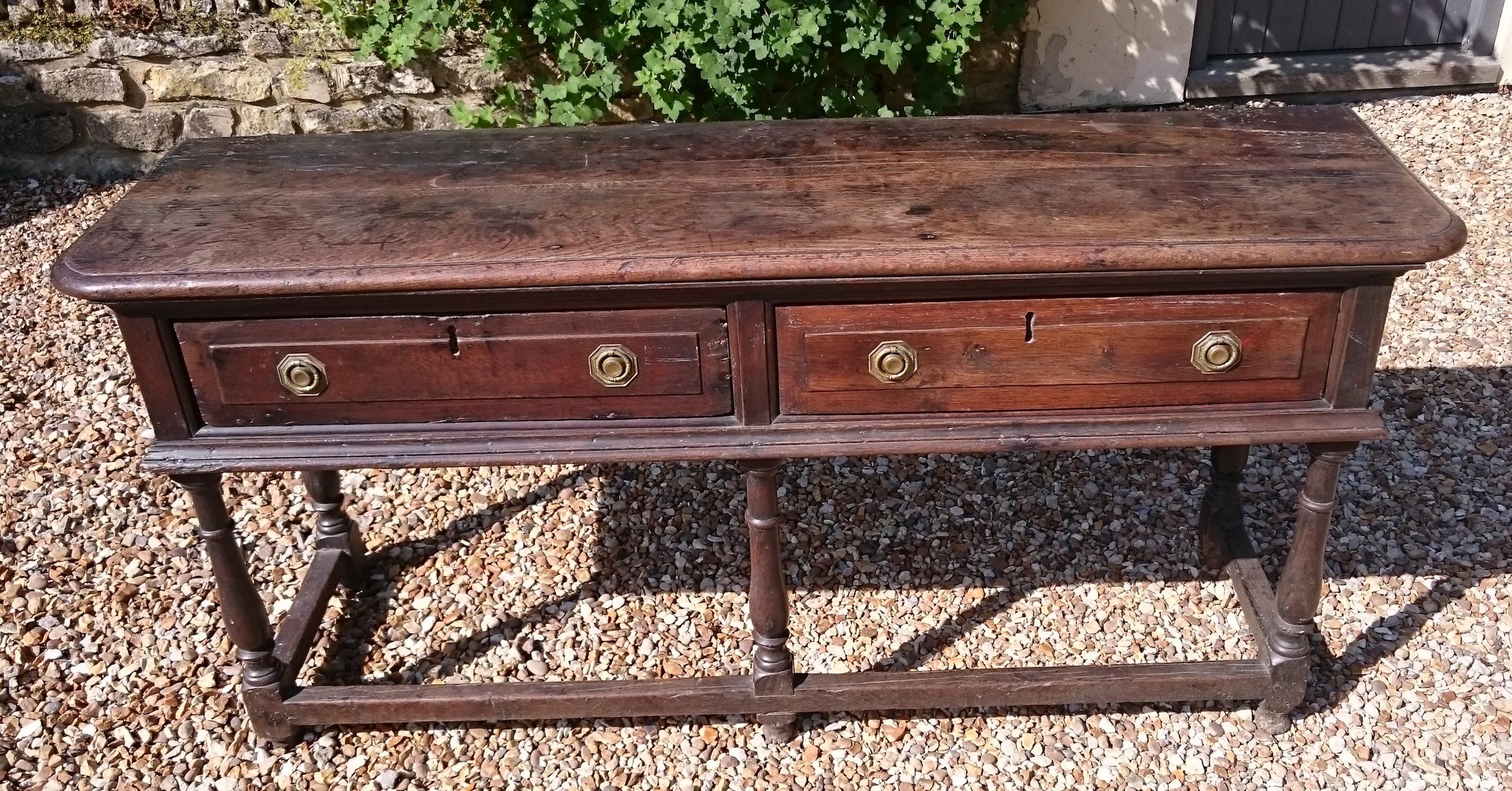 17th century oak dresser standing on elegant turned legs with two drawers in the frieze and lower stretcher. This is a charming little dresser which is a really good color and will look even better when the restorers have polished it with