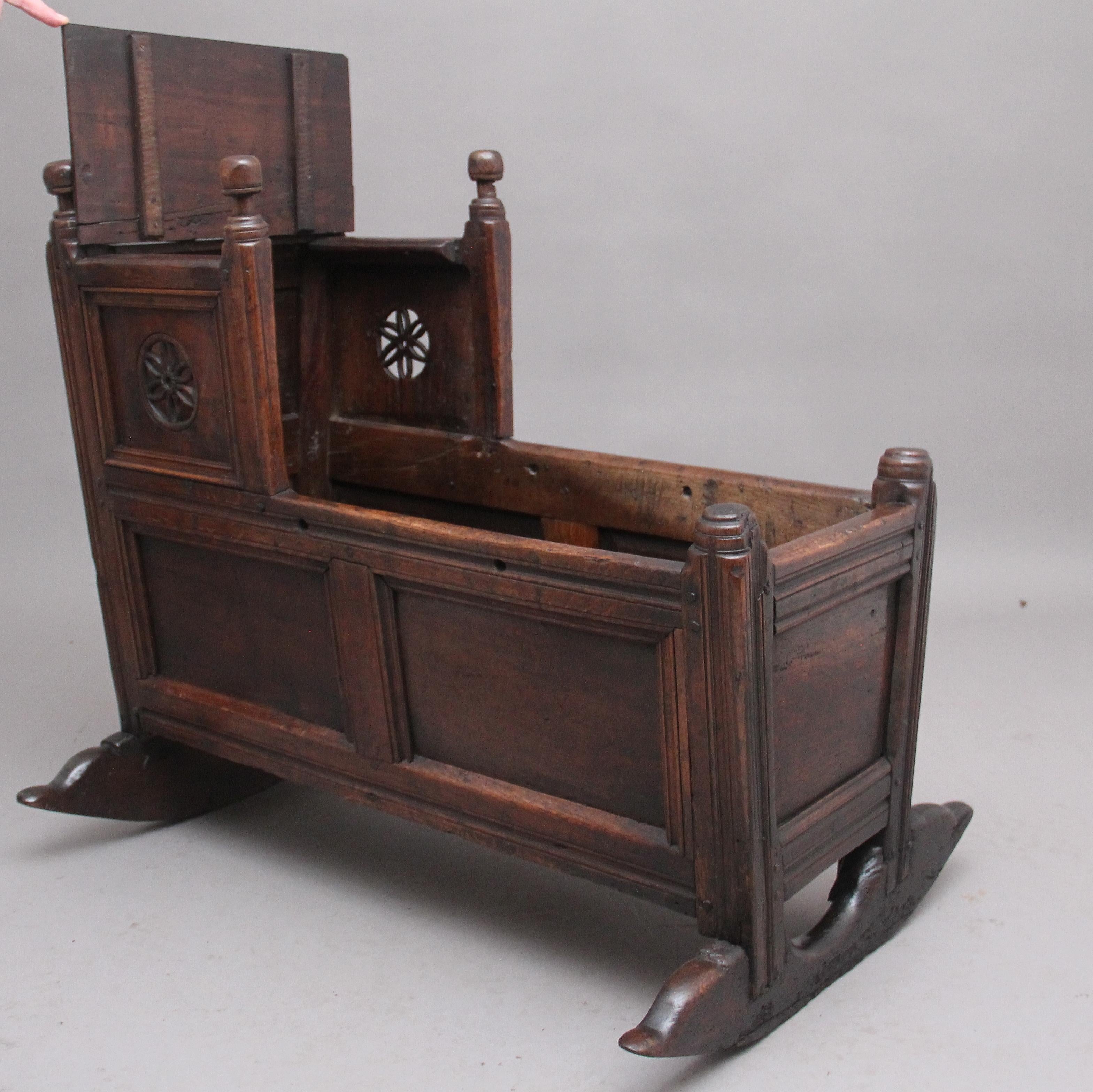 17th century oak cradle with a raised canopy with a hinged lift up lid, decorative pierced carved flower head on each side, panelled sides, at one end of the cradle the top panel is carved with the date 1674 and initials A K. Raised on shaped rocker