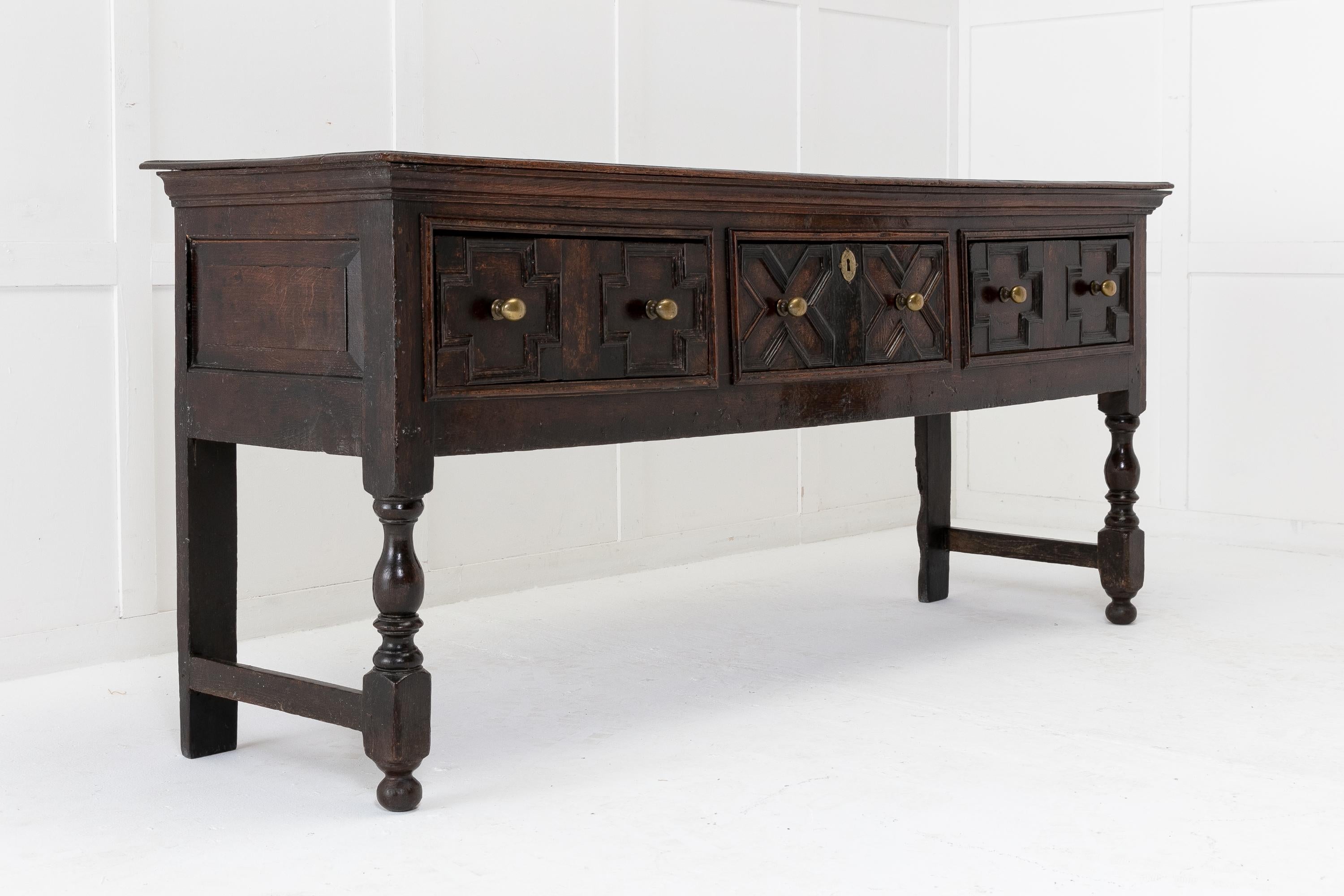 A very nicely proportioned 17th Century oak dresser base having a moulded edge top and three deep drawers below. The drawers have nice geometric carved patterns, and brass handles. The sides have deep fielded panels. Raised on squared back legs and