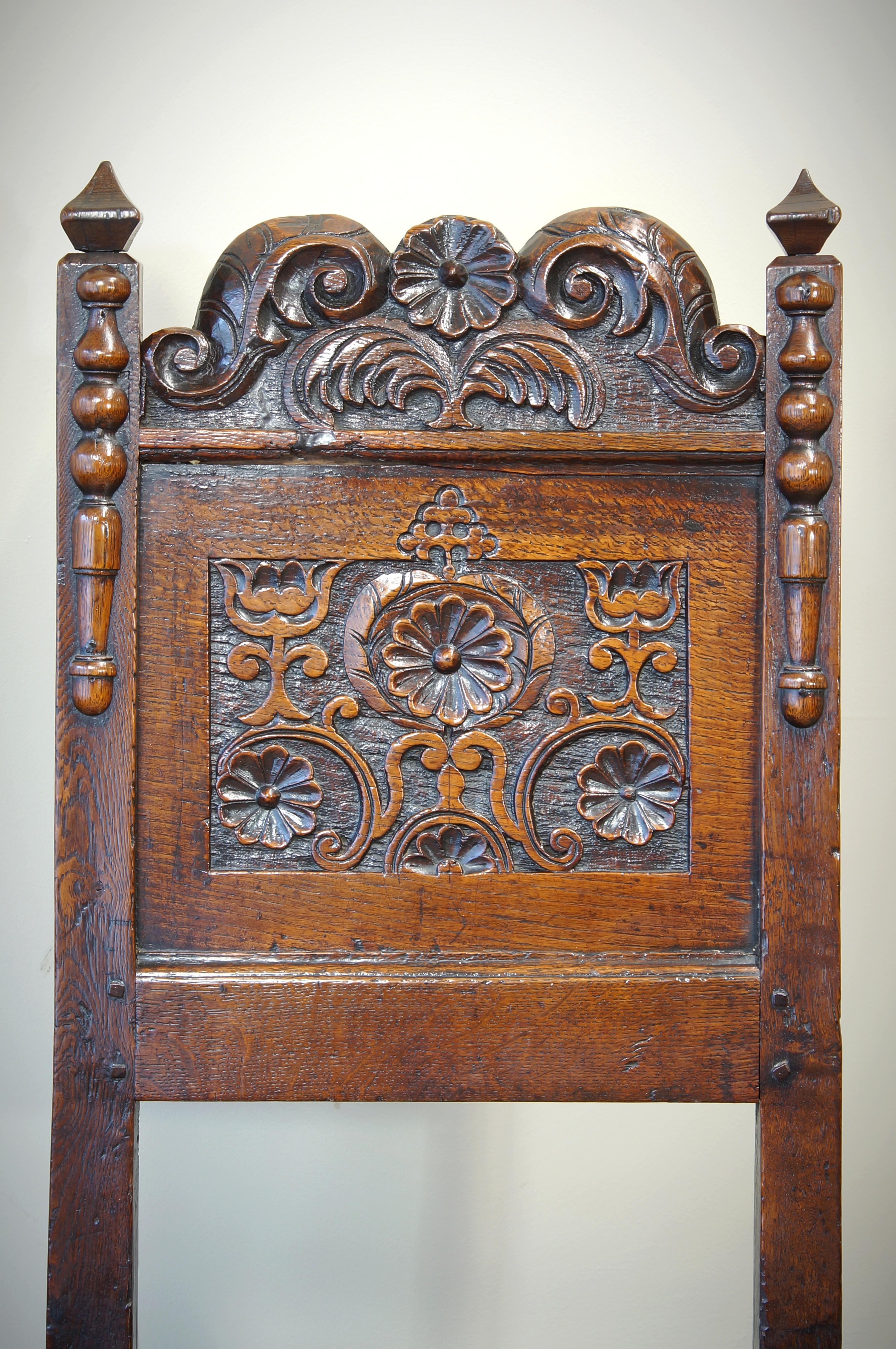 A 17th Century oak backstool from the South Lancashire/ North Cheshire region.
Having a shaped and carved crest, a panel carved with a central daisy flanked by styilsed tulips. The uprights decorated with applied split turnings and pyramid finials,