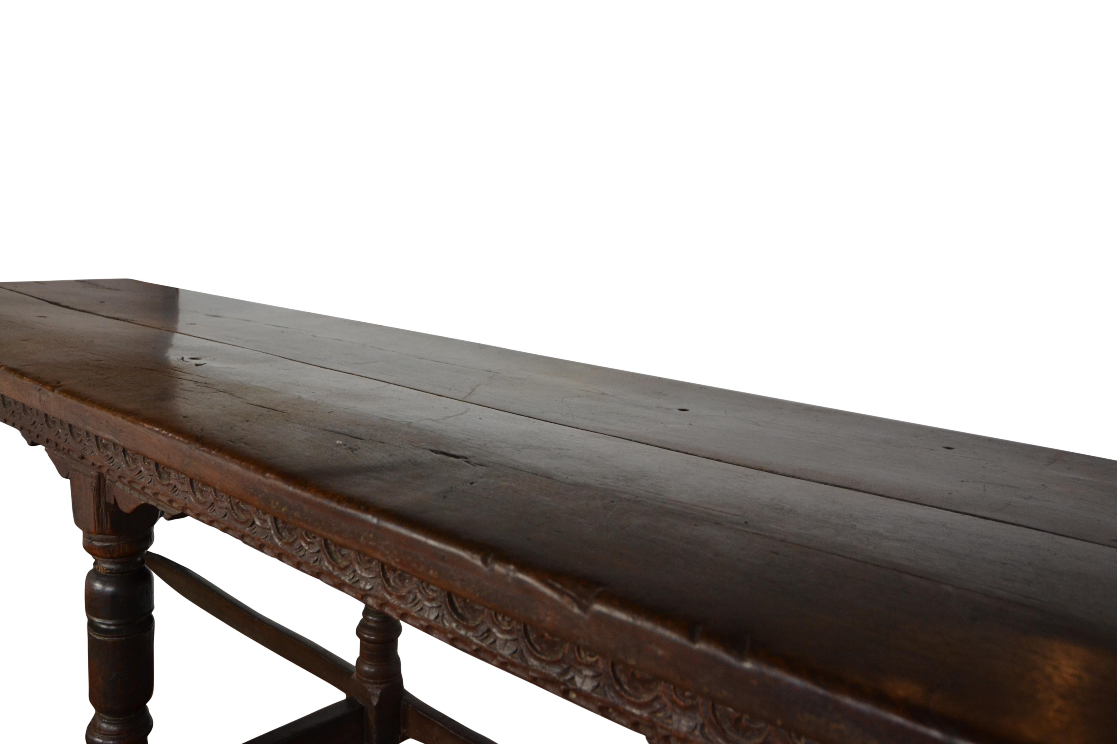 A large English oak refectory table, circa 1680. Carved frieze to one long side, turned legs. Table has original finish and nice patina.