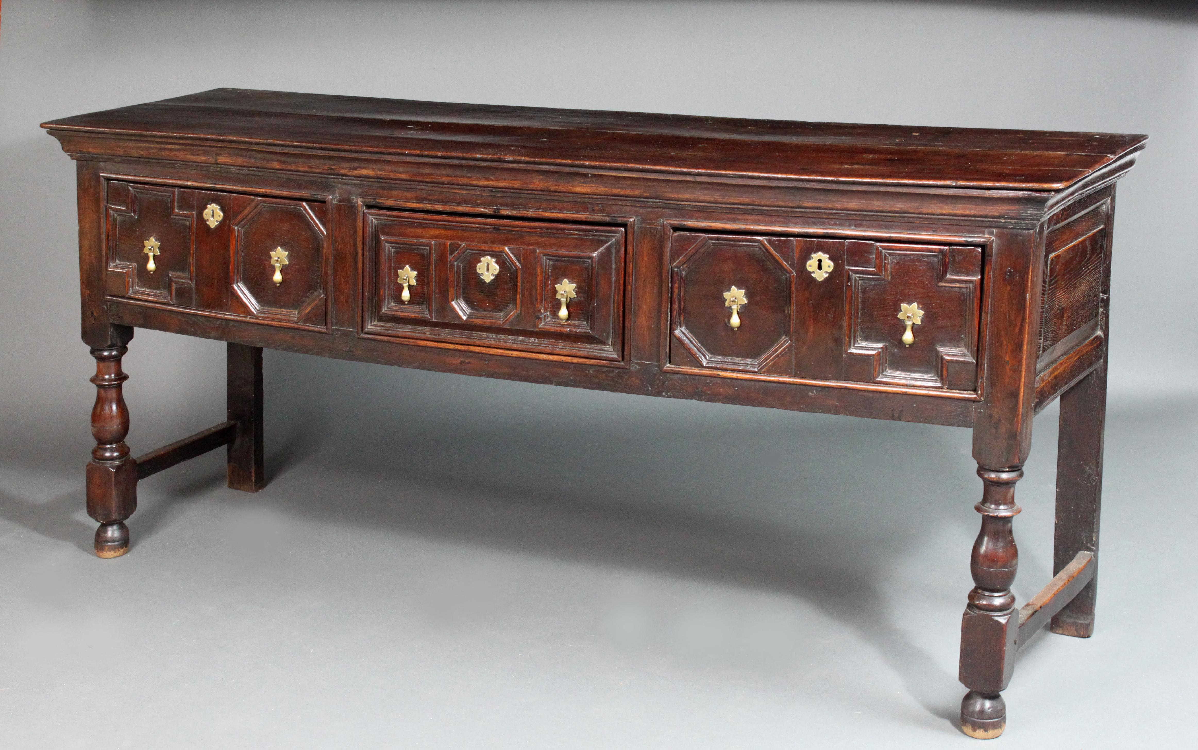 A Charles II oak serving dresser with its original colour and patina and handsome geometric moulded-front drawer fronts, side hung drawers (to stop the drawers from tipping when opened), panelled ends and good turned bulbous baluster legs; the