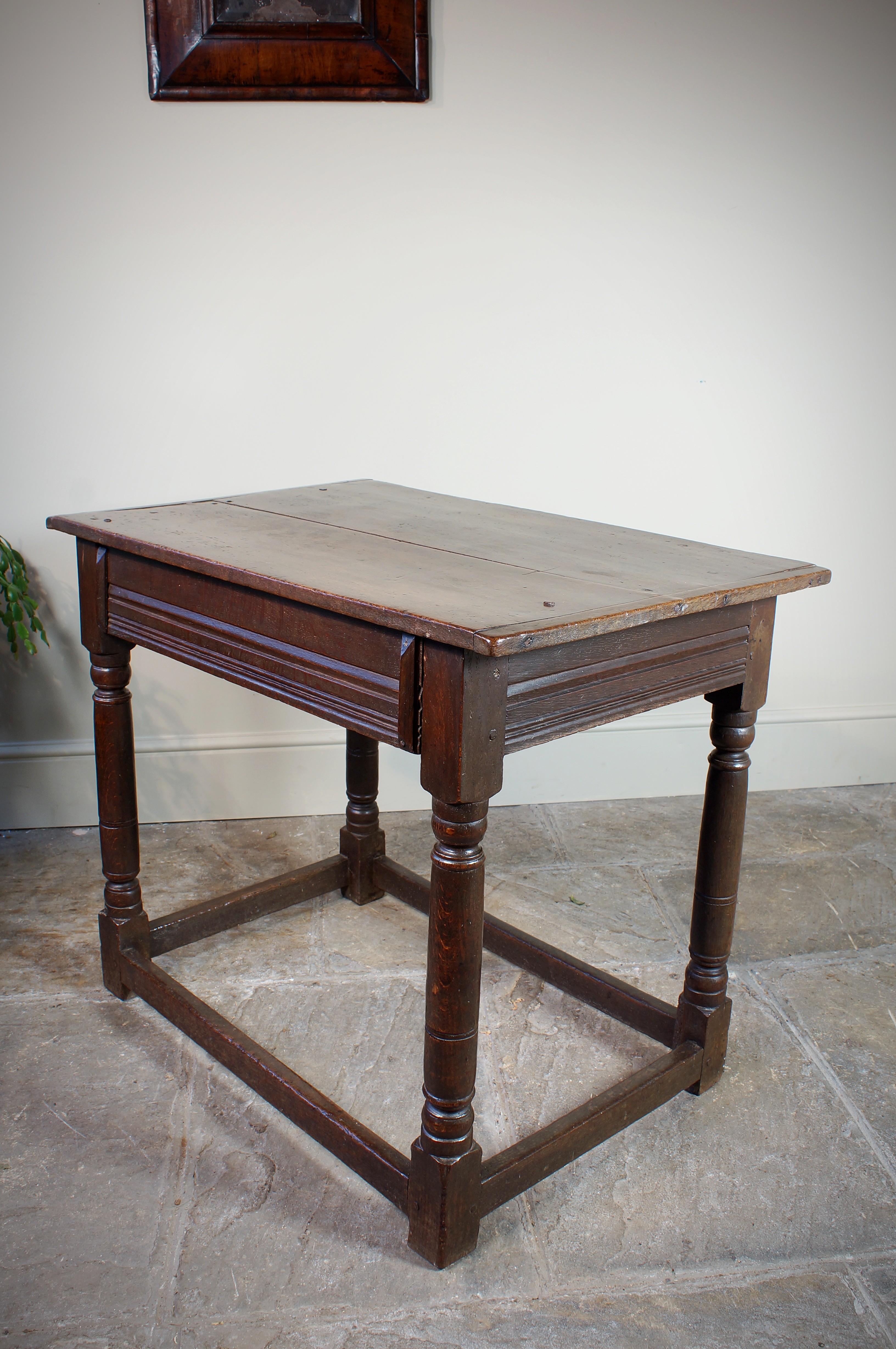 A very pure mid 17th Century joined oak centre table.
Having a two piece cleated top, four gun barrel turned legs, scratch moulded rails and plain stretchers. Unusually the scratch moulding continuing onto the back rail and absence of a drawer