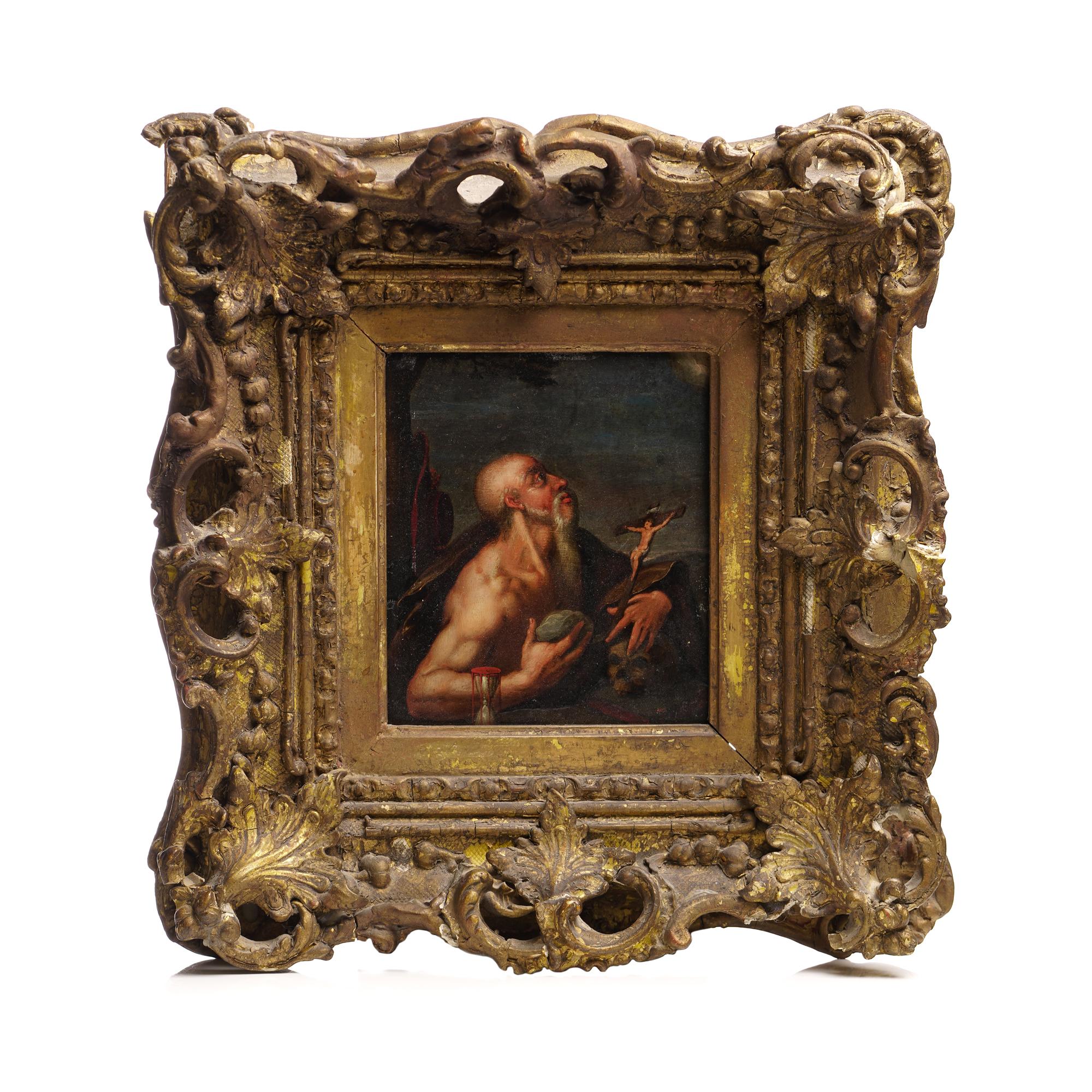 In this antique 17th-century oil painting on copper, we see St. Jerome, encased within an intricately adorned wooden frame. Jerome assumes the role of a penitent, deeply engrossed in meditation while fixating on a crucifix. A striking detail reveals