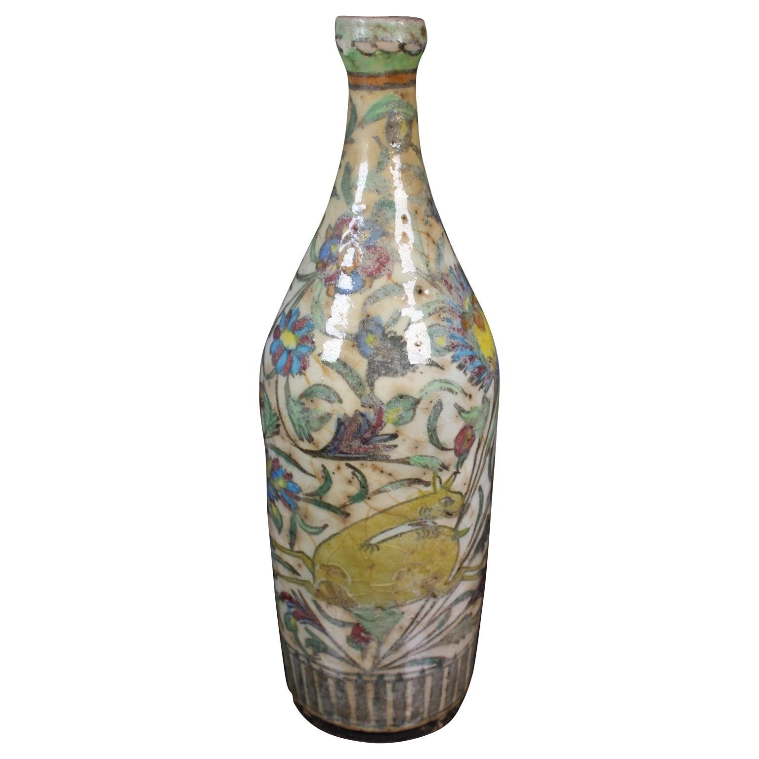 Persian wine bottle or vase that was repaired using a traditional Japanese method called kintsugi. The vase has hand painted flowers and animal details. It is an tan color with greens, blues, and purples.