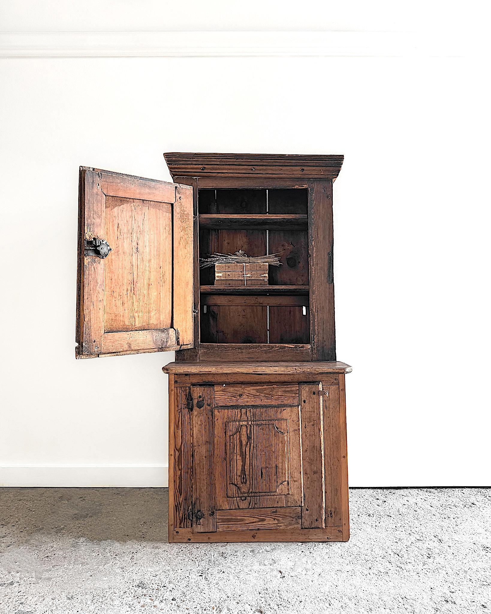 Des siècles d'utilisation ont façonné cette armoire suédoise à dos d'âne du XVIIe siècle en une pièce de caractère. Des panneaux sculptés à la main ornent les portes, dont les bords usés et la patine profonde révèlent le passage du temps. Des