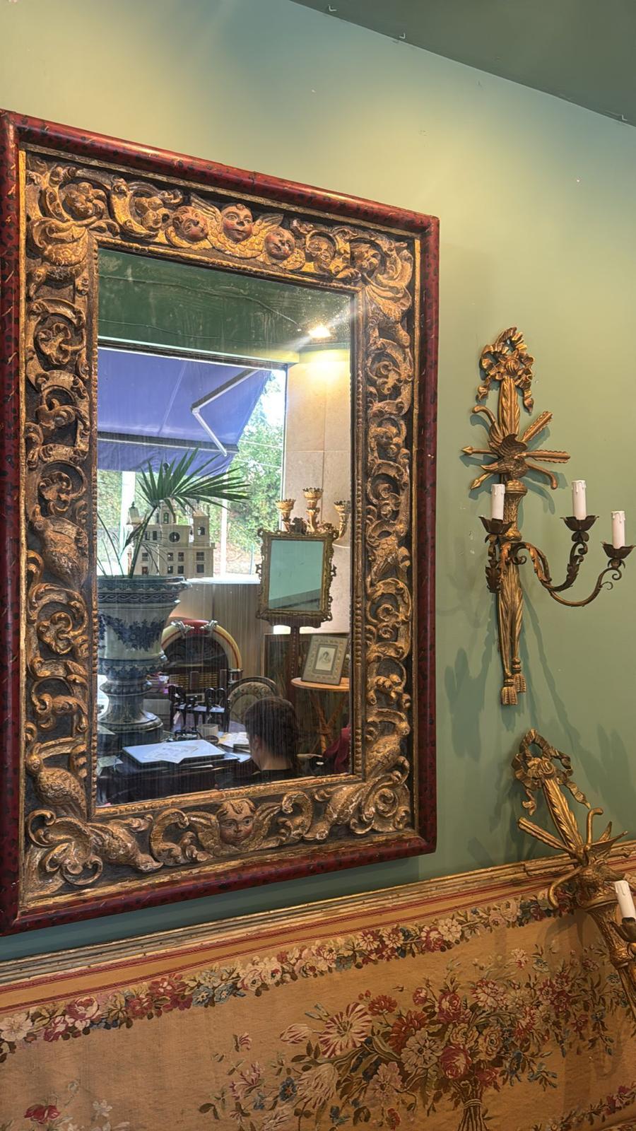 Cet impressionnant miroir portugais du XVIIe siècle est un bel exemple de l'art baroque du bois. Le cadre rectangulaire est richement sculpté et décoré de rinceaux complexes, de motifs floraux et d'une série de visages de chérubins qui ajoutent à la