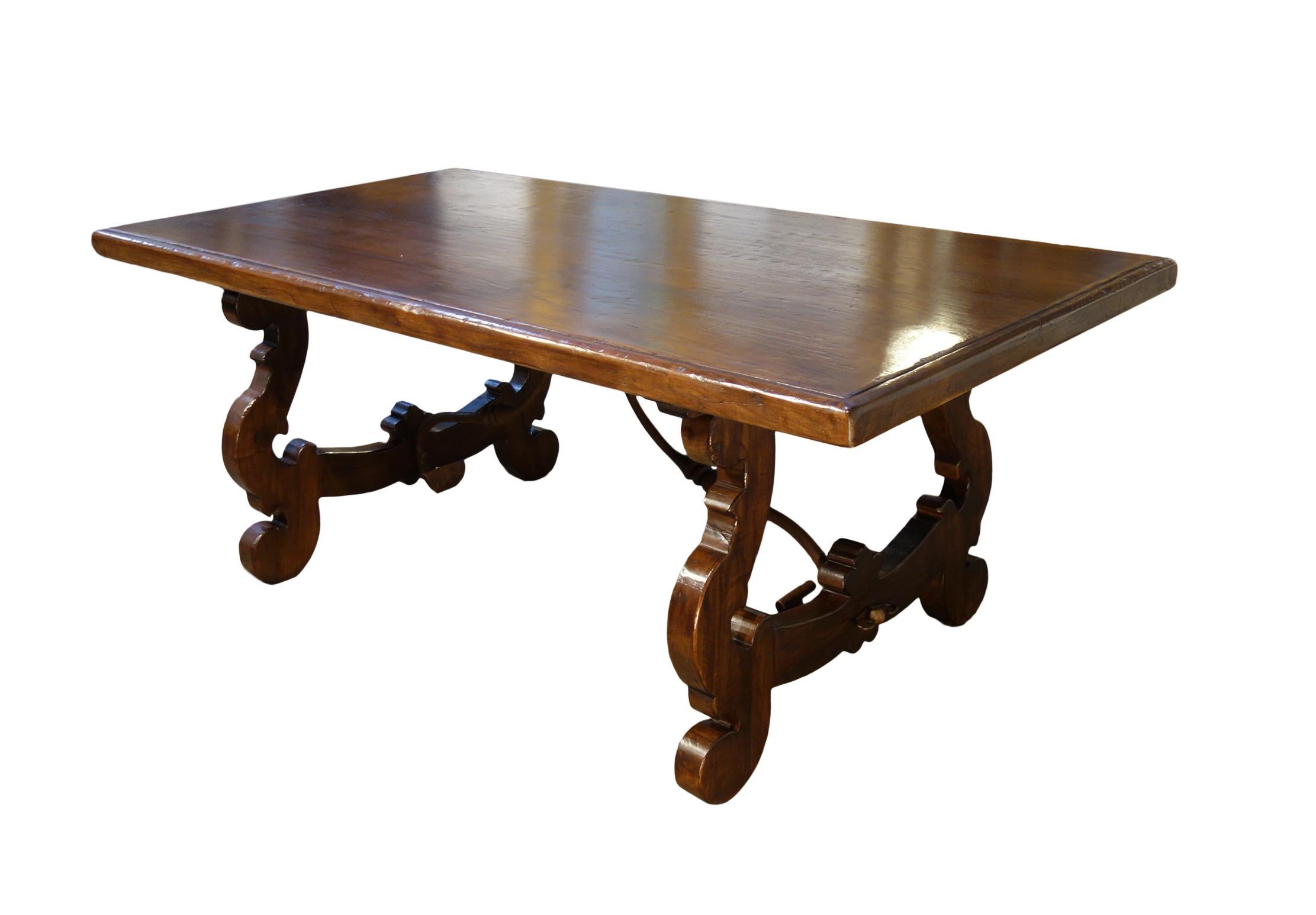 Our classic Lira style dining table: Old Walnut refectory table with sculpted edges, lyre-shaped bases, and hand-forged iron elements and Crafted in aged Italian premium solid walnut, featured in Espresso Dark shellac finish by our Master Craftsmen