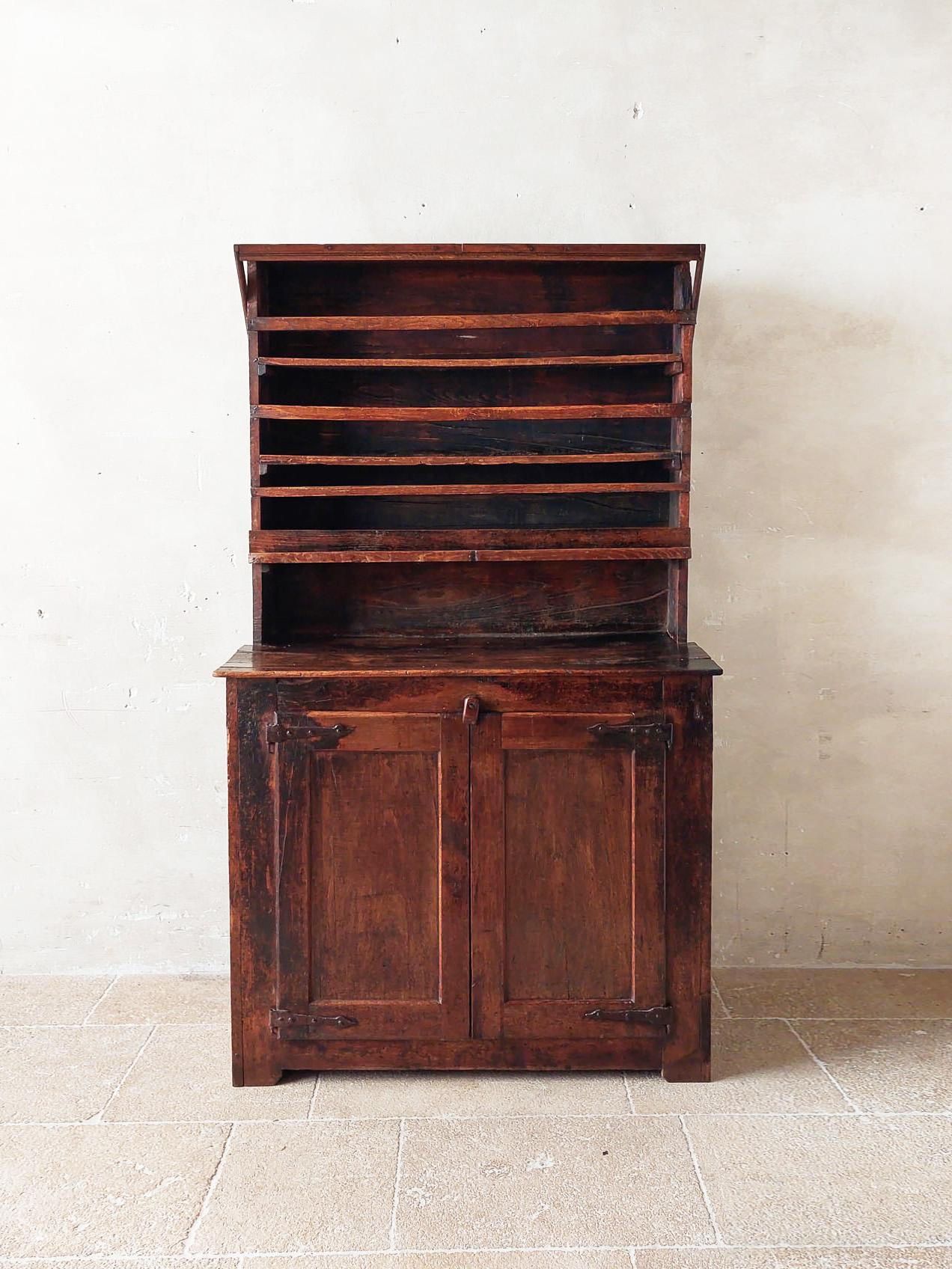 17th century rural French oak kitchen cabinet, wabi-sabi style, partly restored. This stunning primitive wooden cabinet has two doors with wrought iron hinges in the bottom compartment, with on the inside a shelve. The upper compartment has shelves