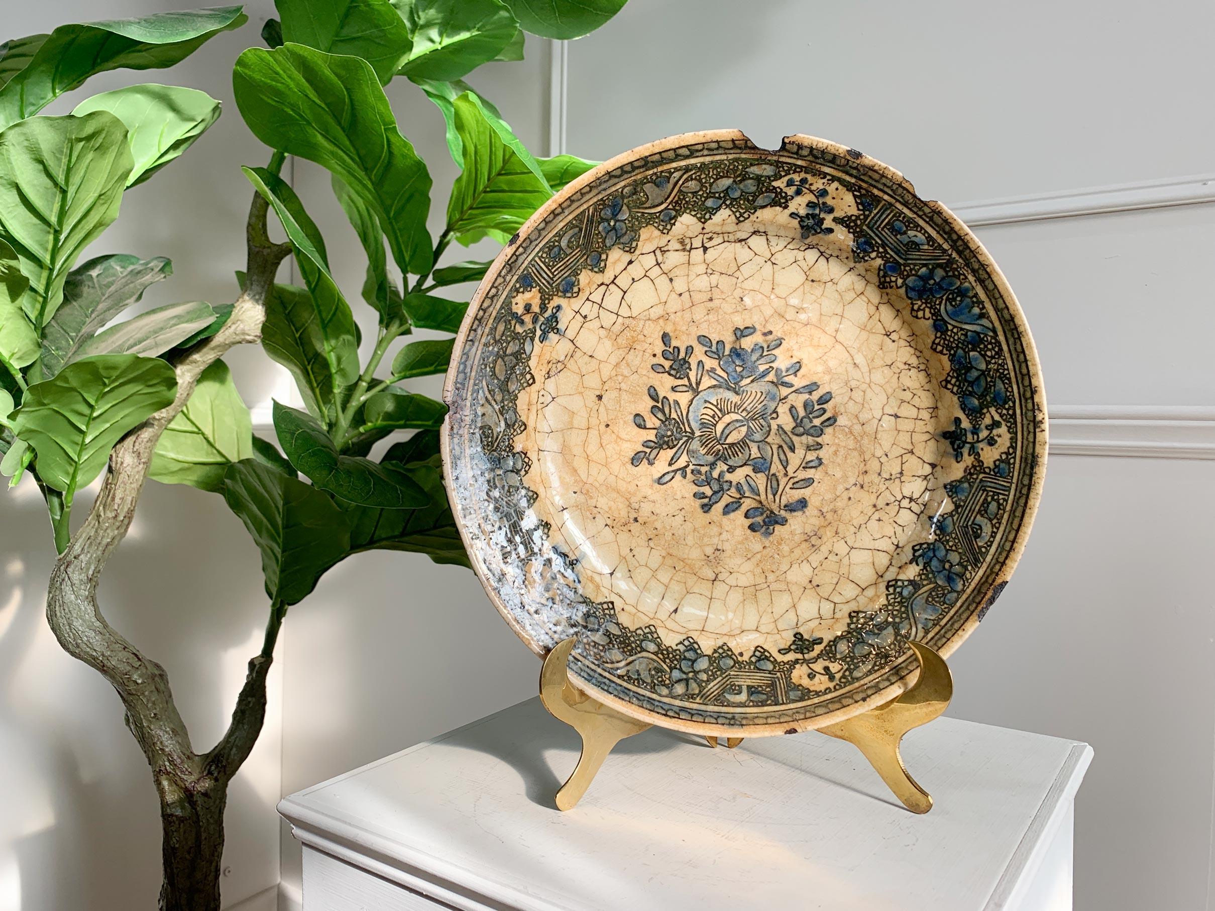Probably Kirman, 16th/17th Century, Persia.
Of Low rounded profile, on short a foot and with sloping rim, this Kirman blue dish with white slip decoration and stylized floral pattern, stained and with obvious loss to rim, structurally sound.


Width