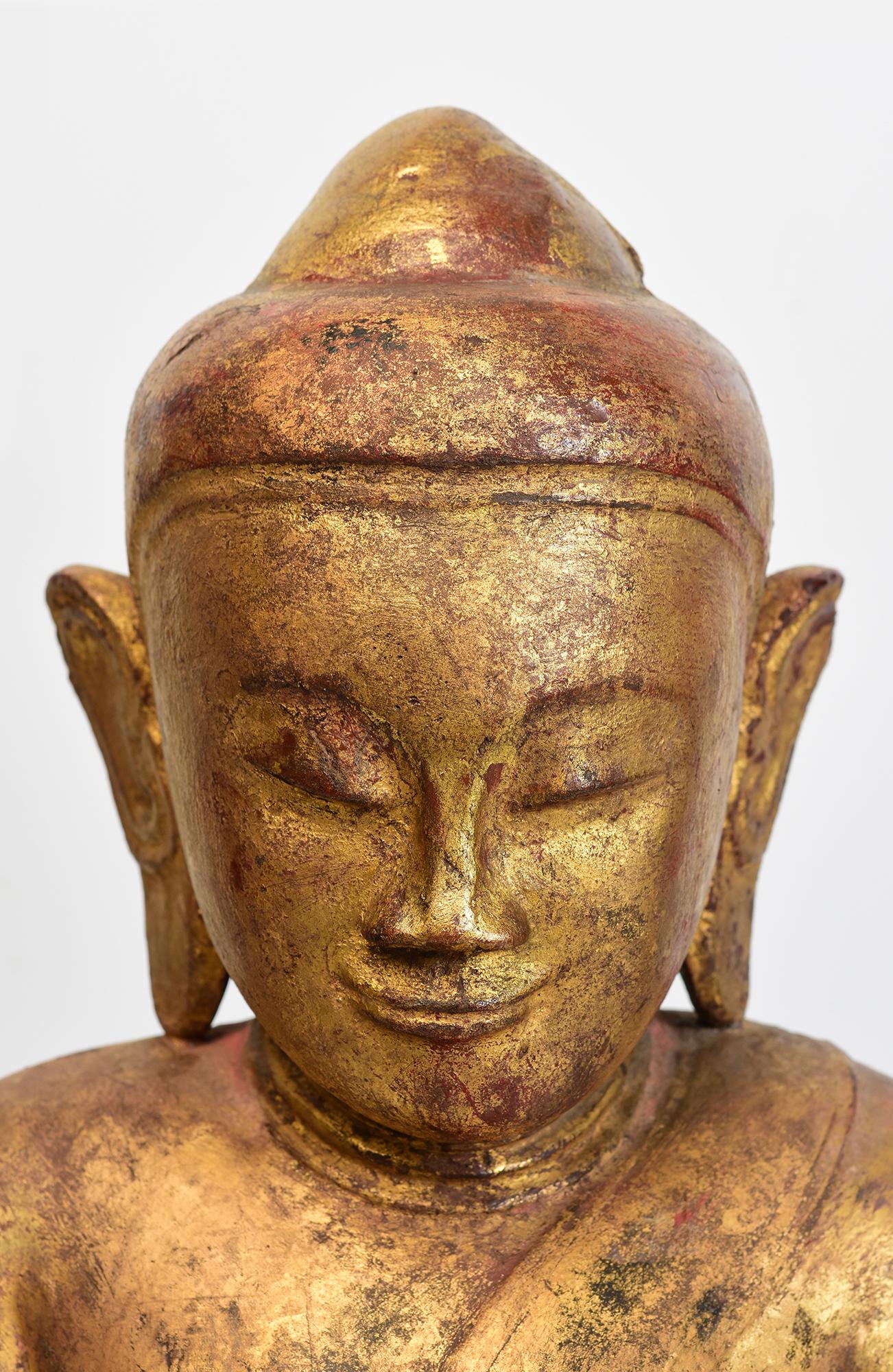 Antique Burmese wooden Buddha sitting in Mara Vijaya (calling the earth to witness) posture on a base with gilded gold.

Age: Burma, Shan Period, 17th Century
Size: Height 48.3 C.M. / Width 29.5 C.M. / Depth 16.5 C.M.
Condition: Nice condition