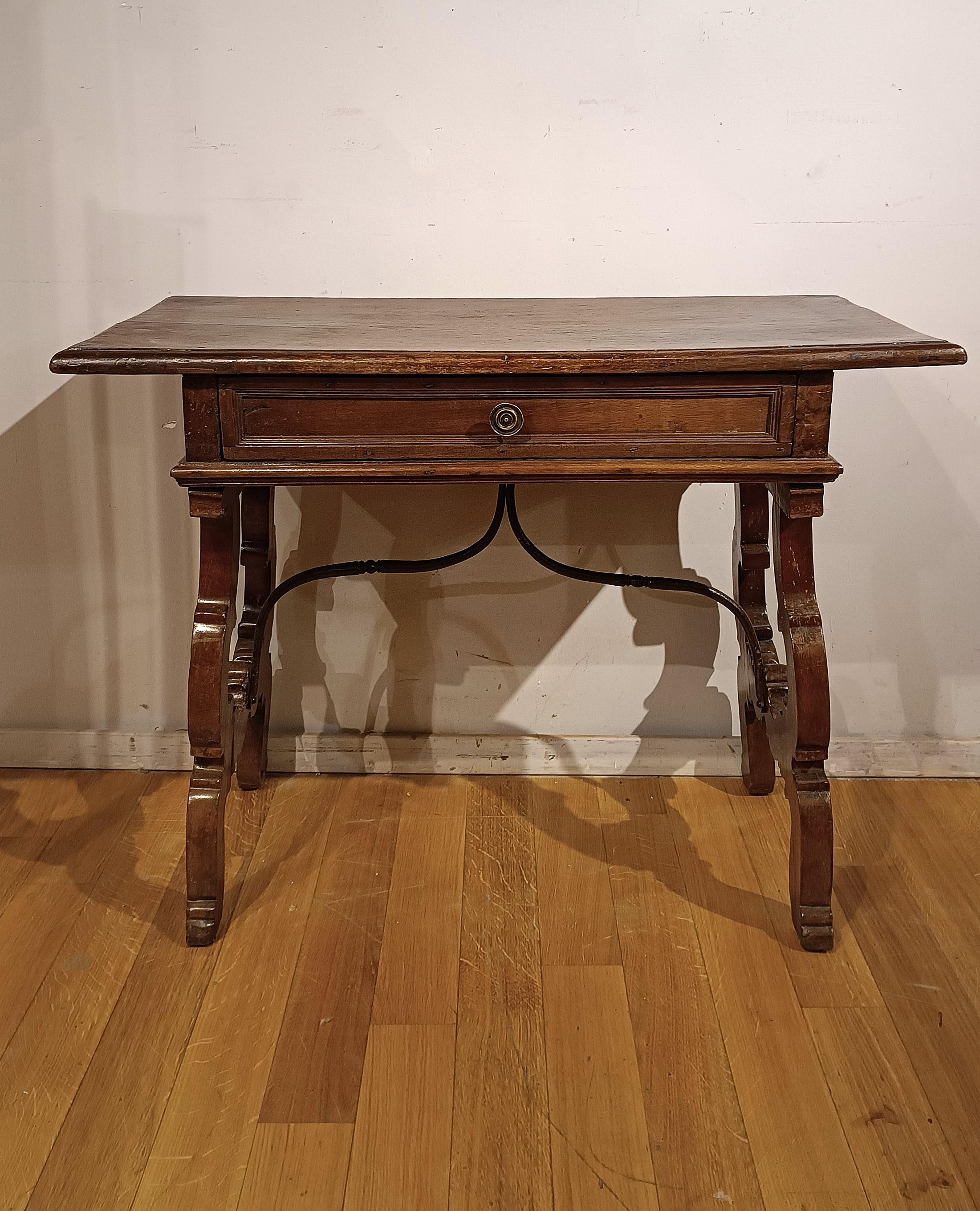 Small writing desk in walnut wood, which can also be used as a side table. Its fine workmanship highlights the elegance of its lyre legs, which are supported on the table by a small iron armature, thus giving a touch of robustness. This desk