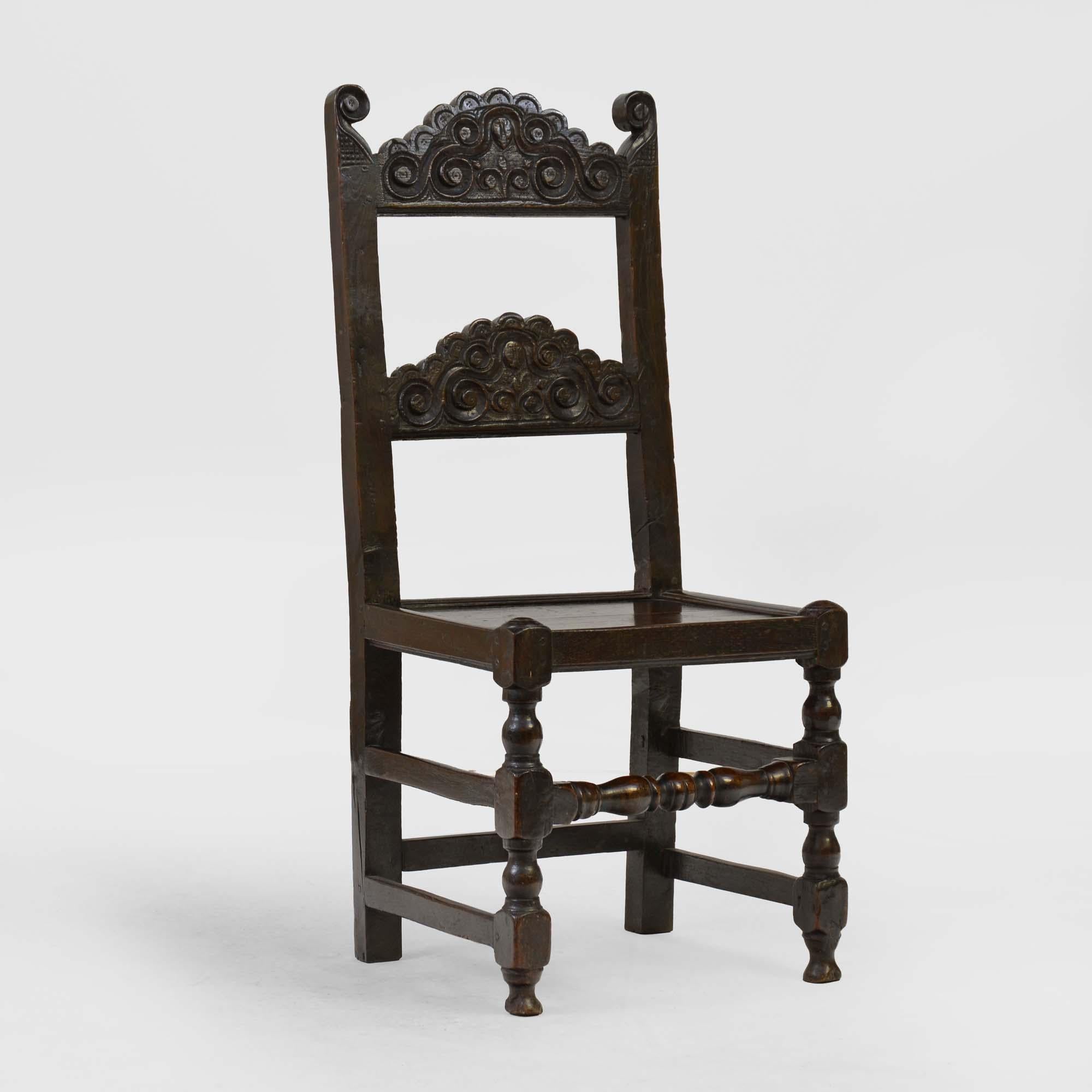 17th century South Yorkshire oak backstool, the two scroll carved arched back to panelled seats over turned and railed under-frame.  
English, circa 1660-1680

By repute the carved centre of the back rails represents the head of Charles I. This
