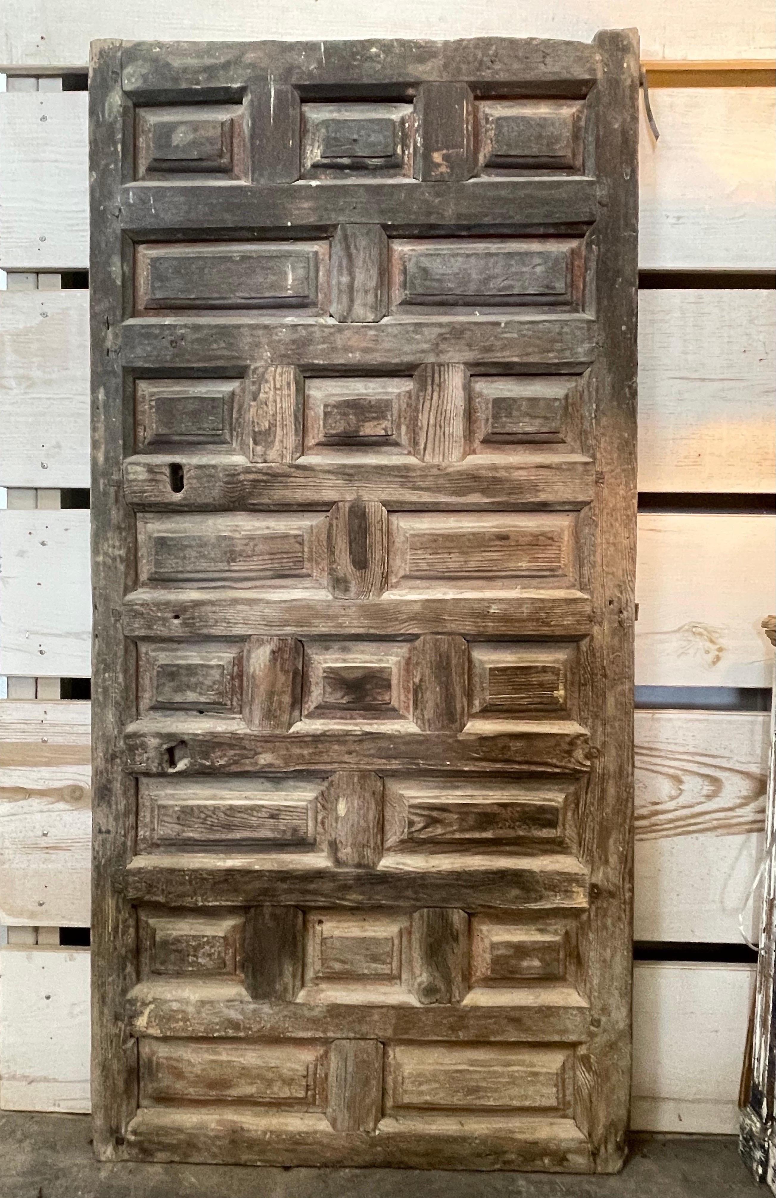 This early Spanish door has remnants of orange paint and shows pegging throughout the door. The wood is the typical Chestnut used often for doors and rustic furniture. On the back is the iron is intact as well the iron that sets out the hinges. It’s