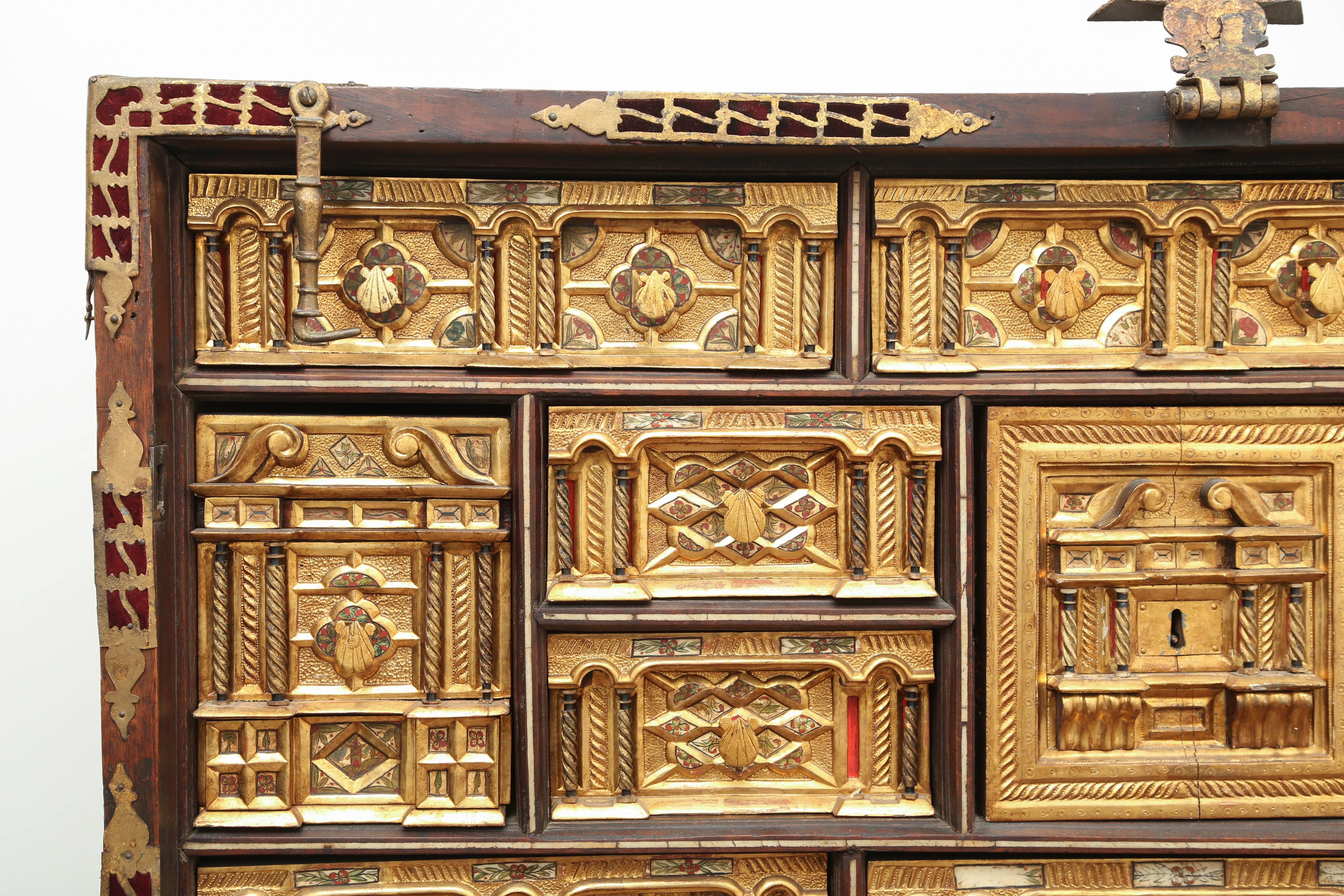 Impressive and rare 17th century giltwood Spanish vargueno with multiple drawers including two hidden behind the door in the center of the cabinet. Each drawer has a gilt bronze clamshell pull. Inlaid polychromed bone decorates each drawer which
