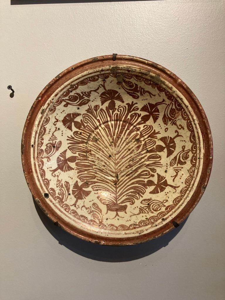 A wonderful, evocative early 17th century Hispano-Moresque lusterware bowl or charger with a central tree of life motif. 
The tin-glazed lusterware produced at Manises near Valencia, Muel, and Catalonia shows the passing of Islamic artistic