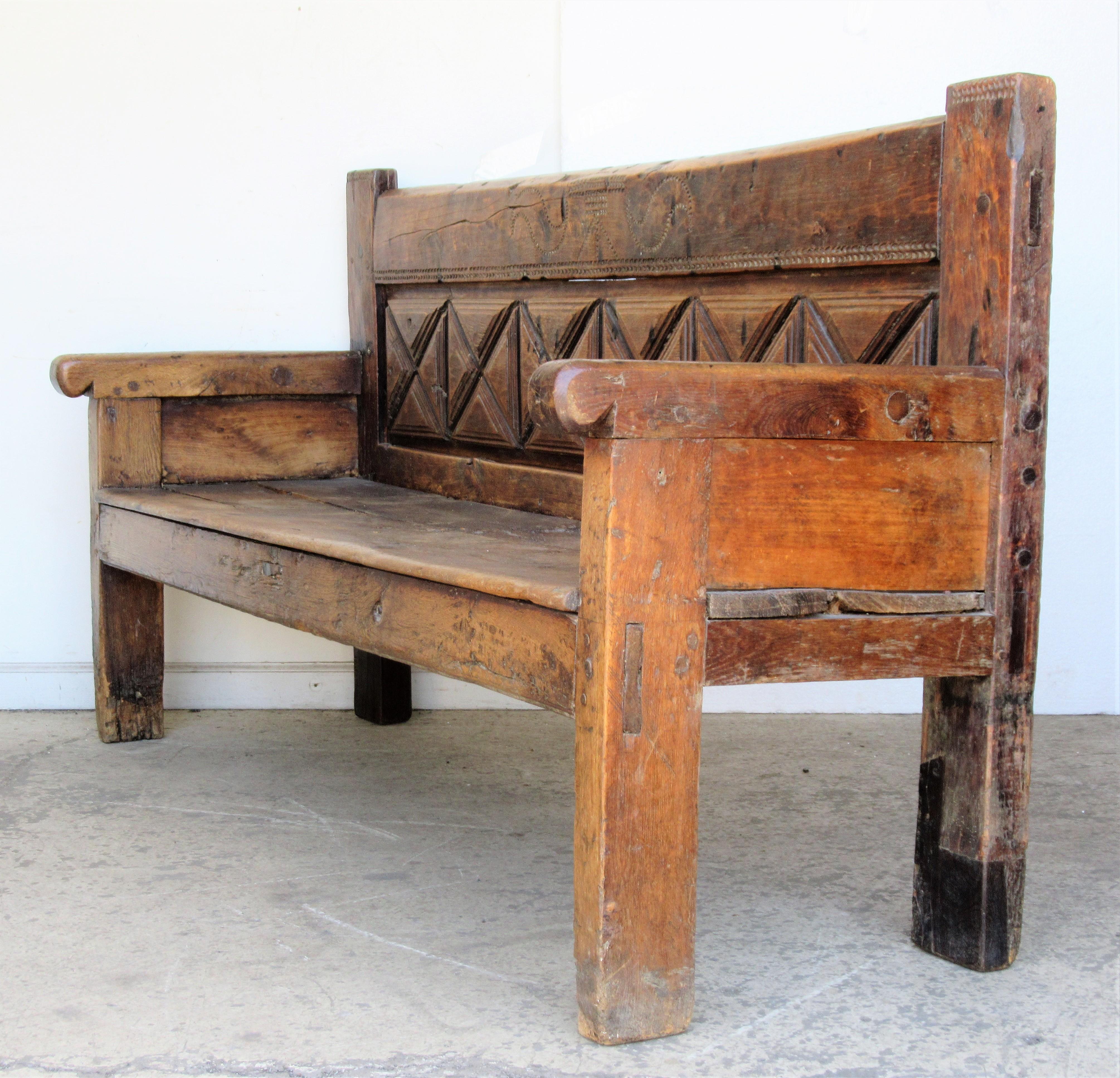Very early Spanish rustic large settle bench with pegged / mortise tenon construction / geometric back with carved details / thick hand hewn boards - all over beautifully aged original old color and surface to wood. A hard to find piece of antique