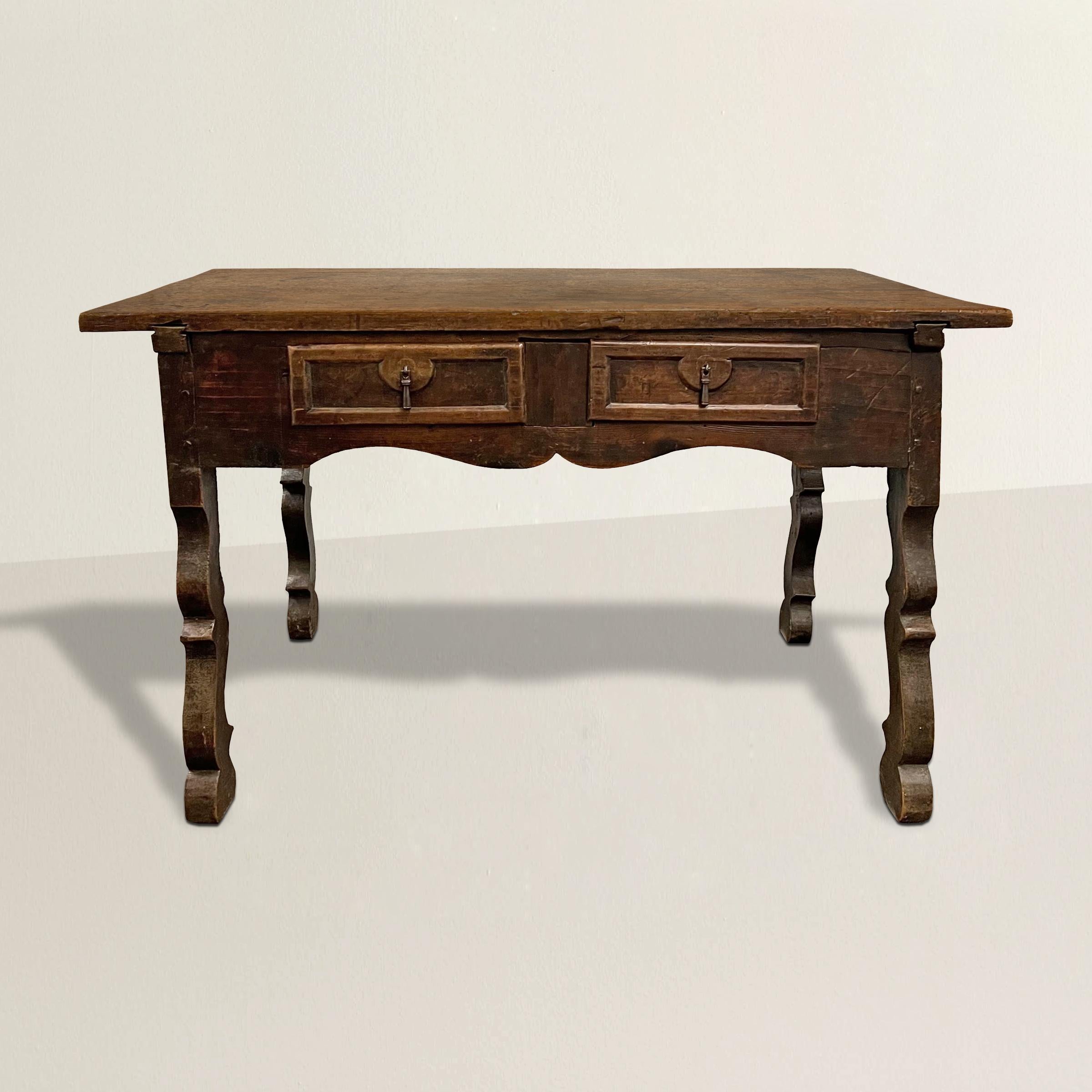 An incredible 17th century Spanish Baroque walnut table with a single walnut slab top over two visible drawers with iron hardware, one hidden drawer, and all resting on silhouetted scrolled legs. Originally a writing table, today it's an amazing