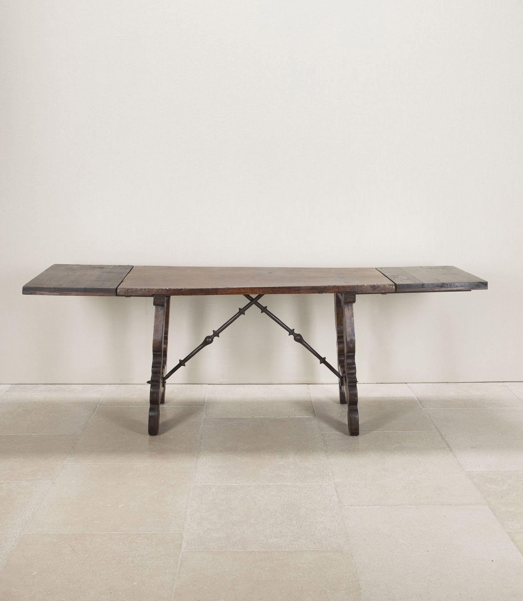 Late 17th Century Spanish walnut top dining table. Beautiful wrought iron cross stretchers to the carved wood base. Beautifully, worn top with wonderful traces of old circumference drawing and other marks that bear witness to its long history.In the