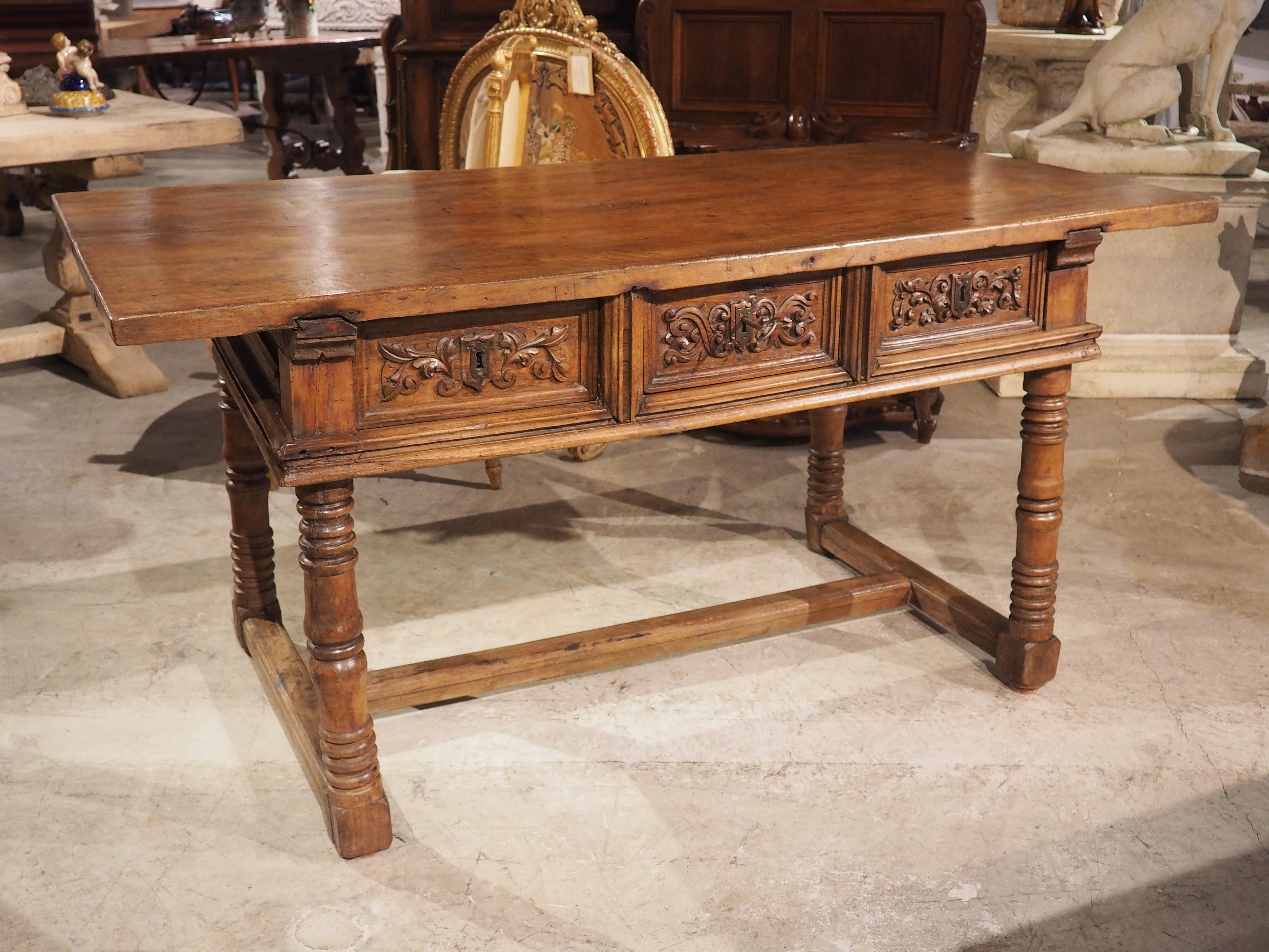 Ein wunderschön gearbeiteter Holztisch aus Spanien. Das Nussbaumholz wurde am Ende der Renaissance (in den 1600er Jahren) handgeschnitzt. Wie bei den meisten spanischen Renaissancetischen ruht die 1 ½