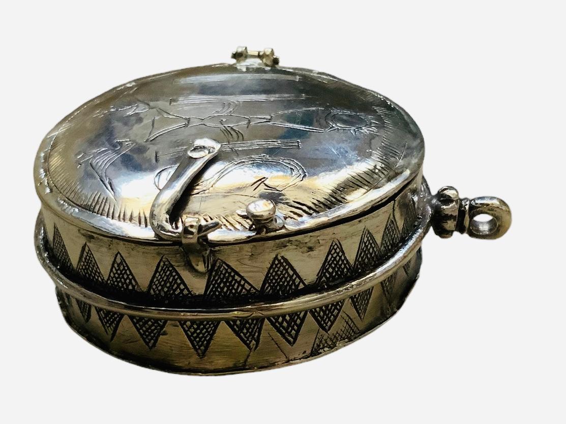 Il s'agit d'un pendentif en argent sterling en forme de boîte ronde pour le pain de l'eucharistie et le reliquaire de voyage du 17e siècle. Il représente un boîtier rond à large charnière, gravé sur le devant d'un christogramme IHS (signifiant