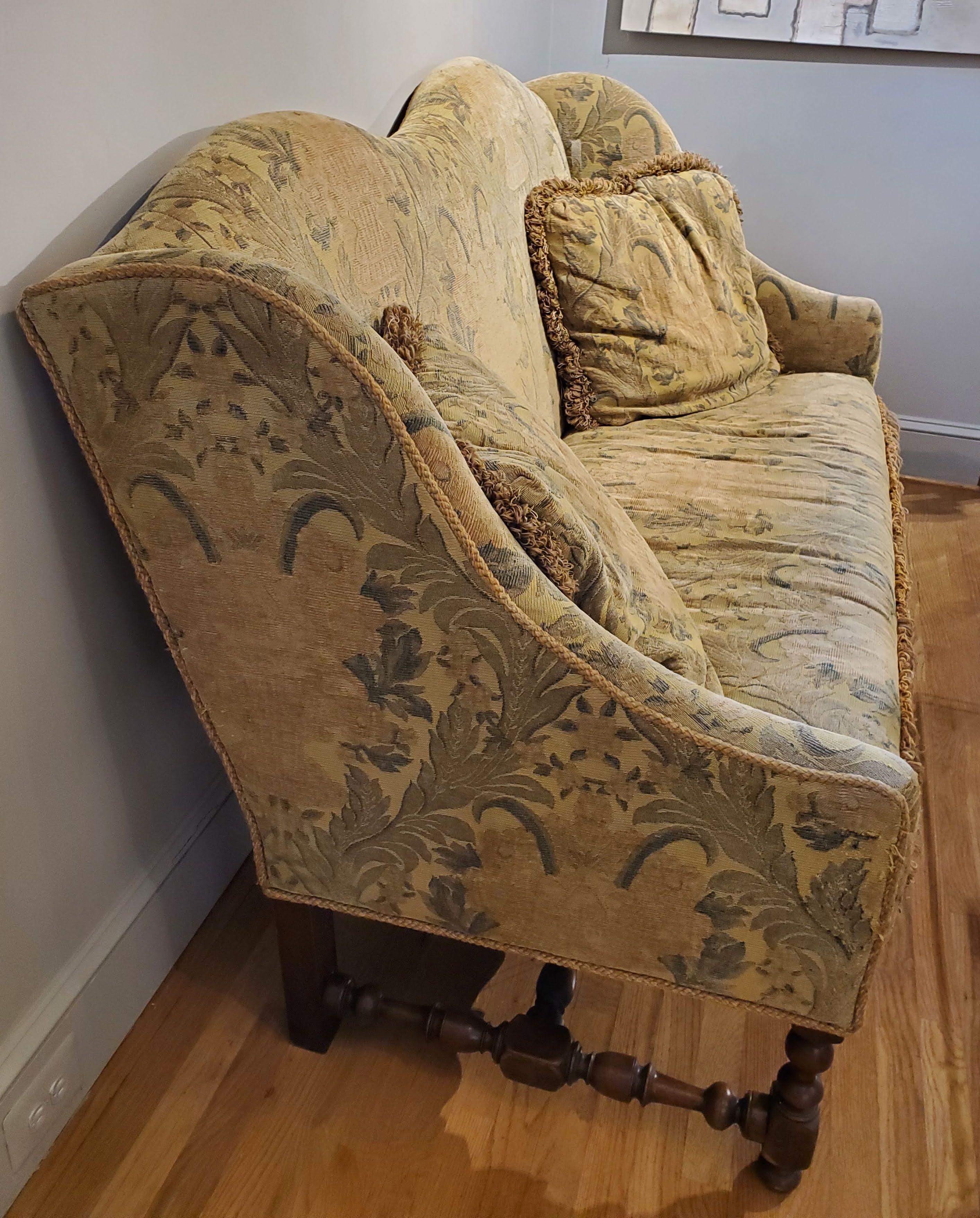 Beautiful 17th century style French Provincial upholstered walnut settee. Arched back with wing shaped ends over intricately turned legs and stretchers. Vintage embroidered fabric. Extremely comfortable. 
Measures: 44” H, 67” W, 30” D.