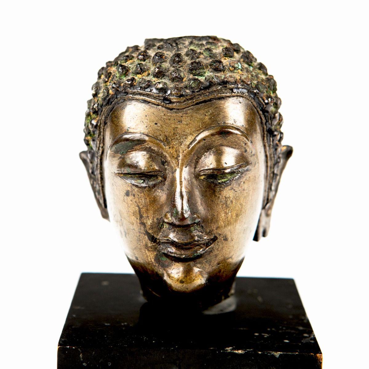 Tête de bouddha en bronze de Thaïlande (années 1600-1700), montée librement sur une base en bois peinte en noir.

La tête présente une belle expression sereine, tandis que le bronze présente une patine naturelle liée à l'âge.

Thaïlande (Siam),
