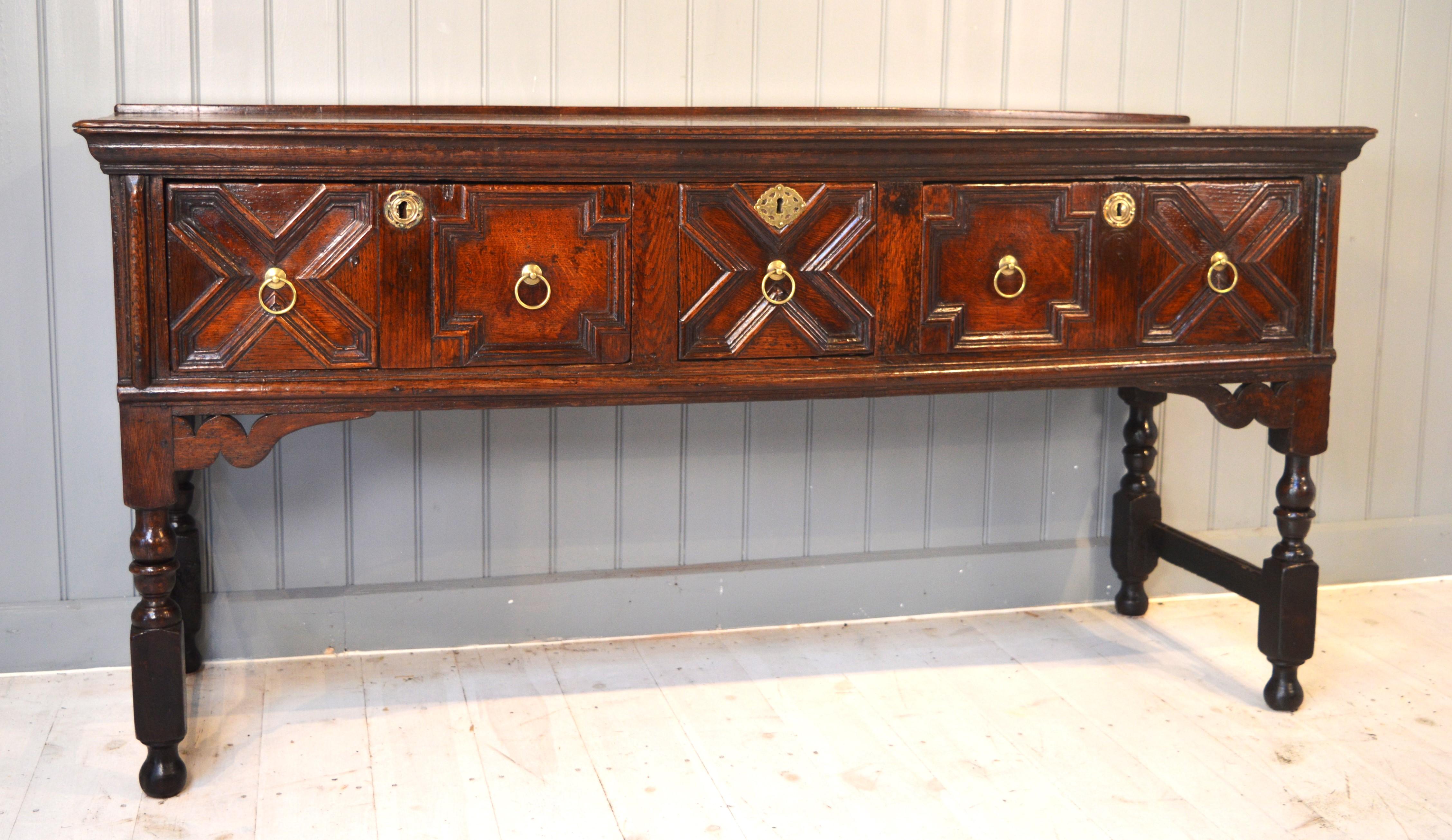 Charming late 17th century oak low dresser of small proportions. The beautifully patinated
top has a plate rail at the back.
The drawers are geometrically moulded with the usual early form of construction, the linings being nailed and the drawers