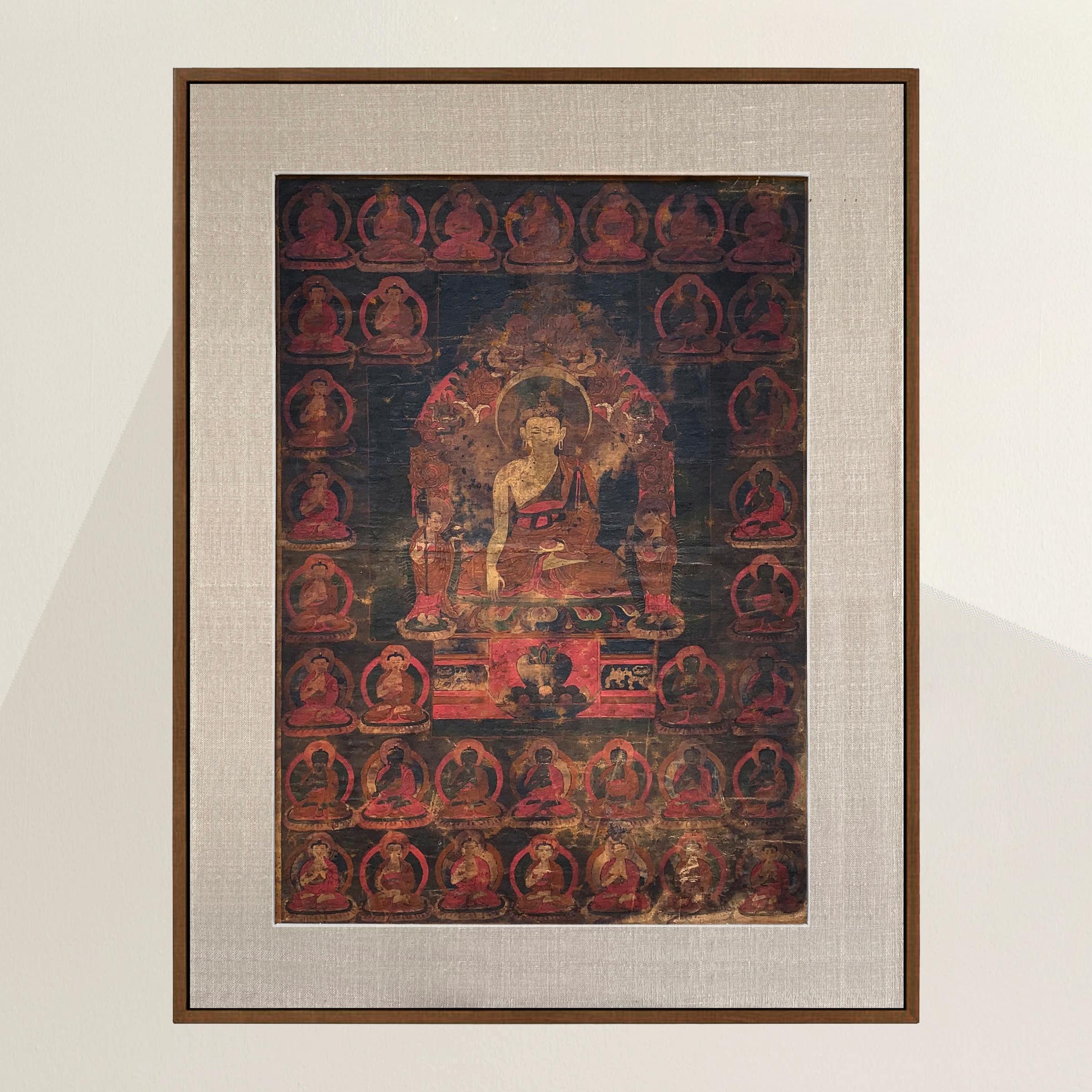 An incredible and rare 17th century (Ming Dynasty) Tibetan Thangka depicting the Medicine Buddha seated on a lotus throne with an alms bowl in one hand, and his other hand with outstretched fingers touching the ground, feeling the pulse of the