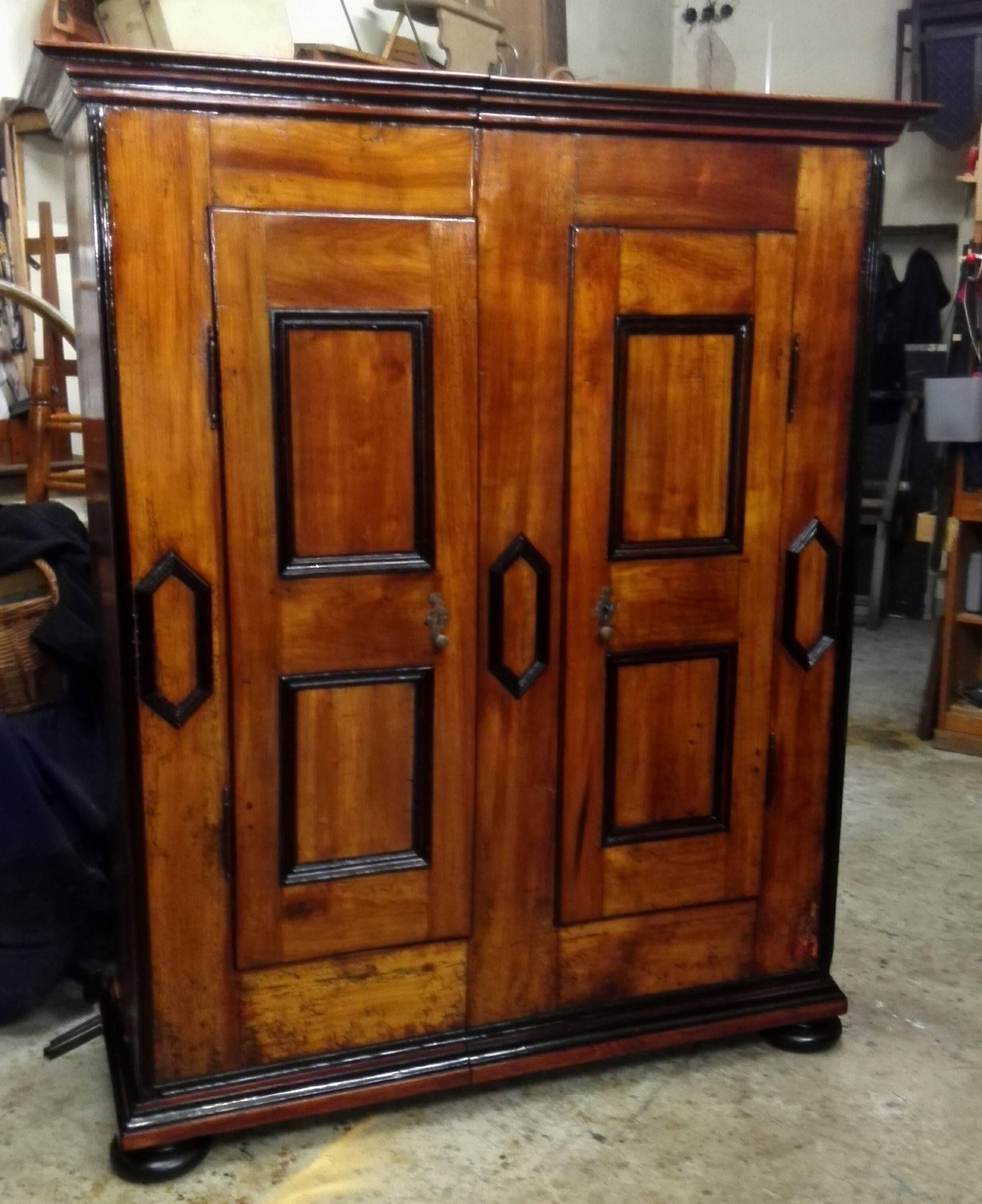 This two-door Swiss plank cabinet in solid sherry wood. It is divided vertically in two! The doors hing on Handdorfer Joints and divided into two panels. The lock is the original and works perfect. The also hand-forged sliding bold and the fittings
