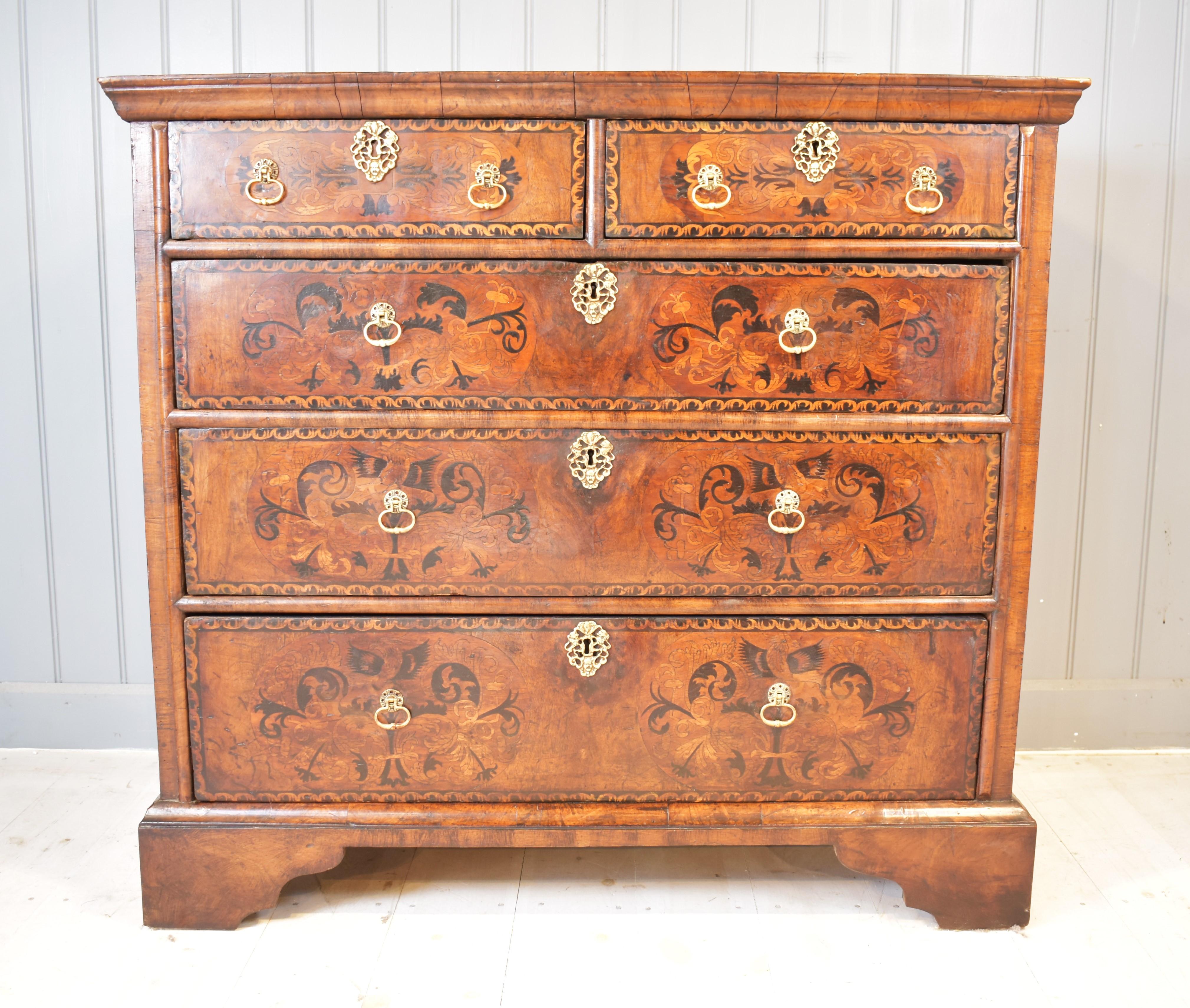 A 17th century walnut marquetry chest of drawers from the William and Mary period, 1689-1702. It has an ogee moulded top with original toffee colour patina. The border is inlaid on the top and the front has decorative floral panels of marquetry