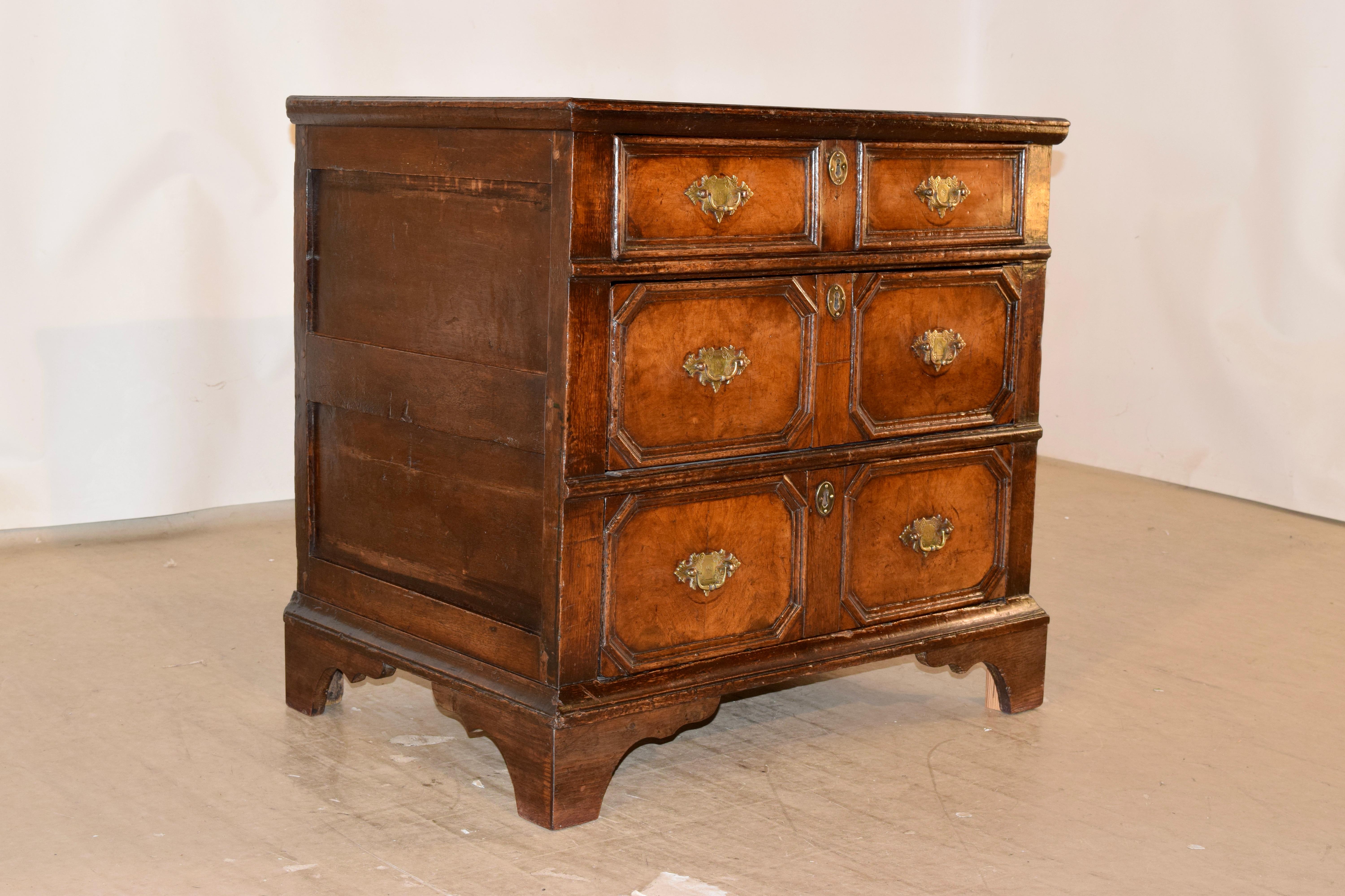 Third quarter 17th century English paneled chest of drawers made from walnut and oak. The top is made from oak planks and has a molded edge, following down to hand-paneled sides and three raised paneled drawers with burl walnut drawer fronts. The