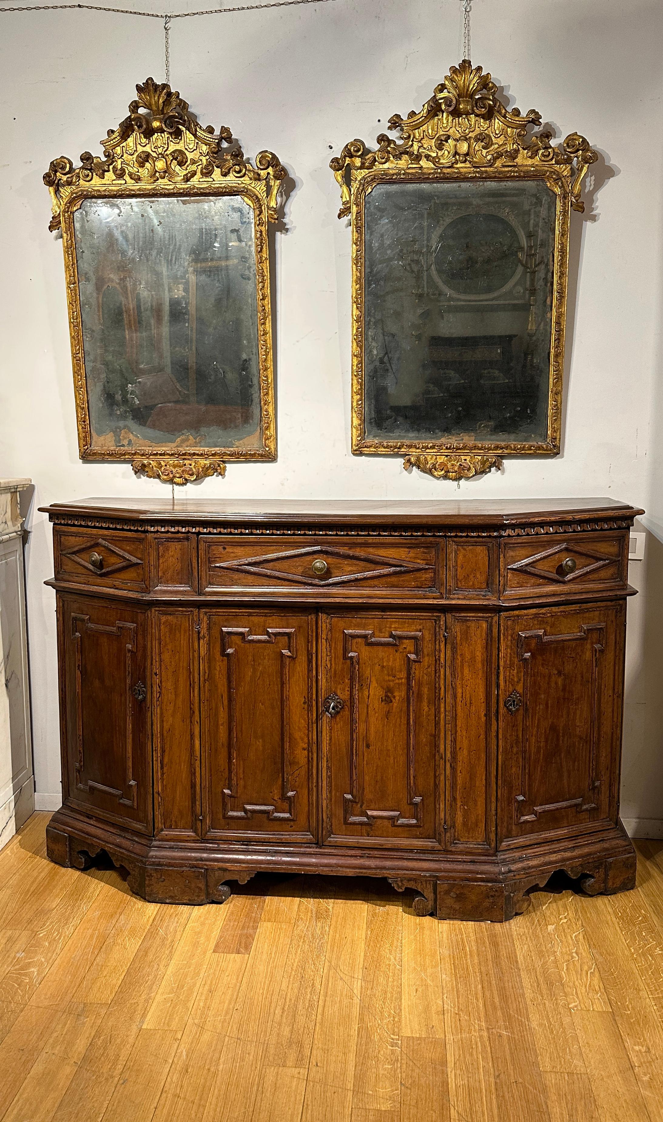 This solid walnut recessed sideboard is an authentic jewel of Tuscan manufacturing from the first half of the 17th century, dating back to the period of the Grand Duchy of Tuscany. The four drawers and the four doors, enriched by geometric frames