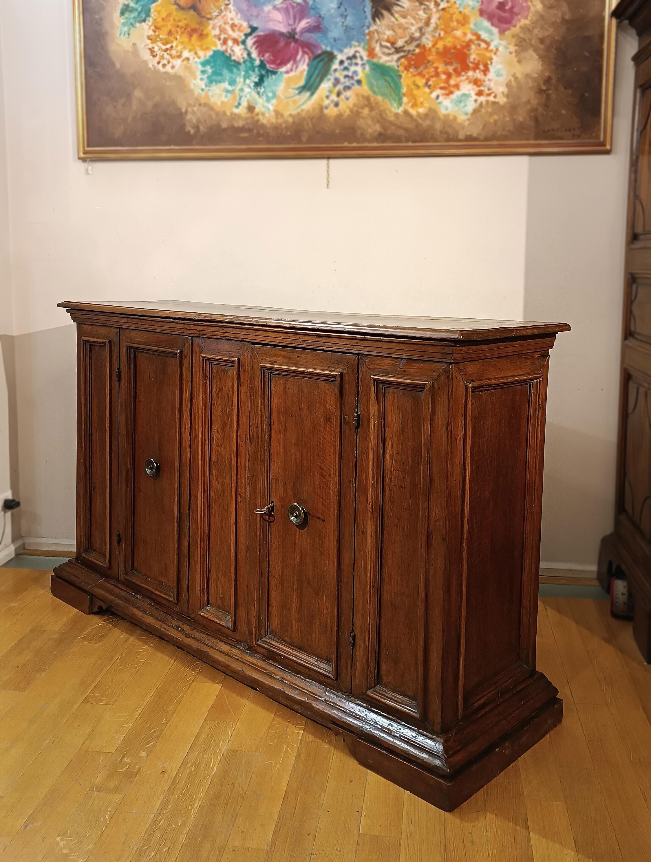 Splendid hand-carved solid walnut sideboard, characterized by timeless elegance. The sideboard is characterized on the front by linear and geometric motifs that enhance its design. It is equipped with two doors, one of which is provided with a key,