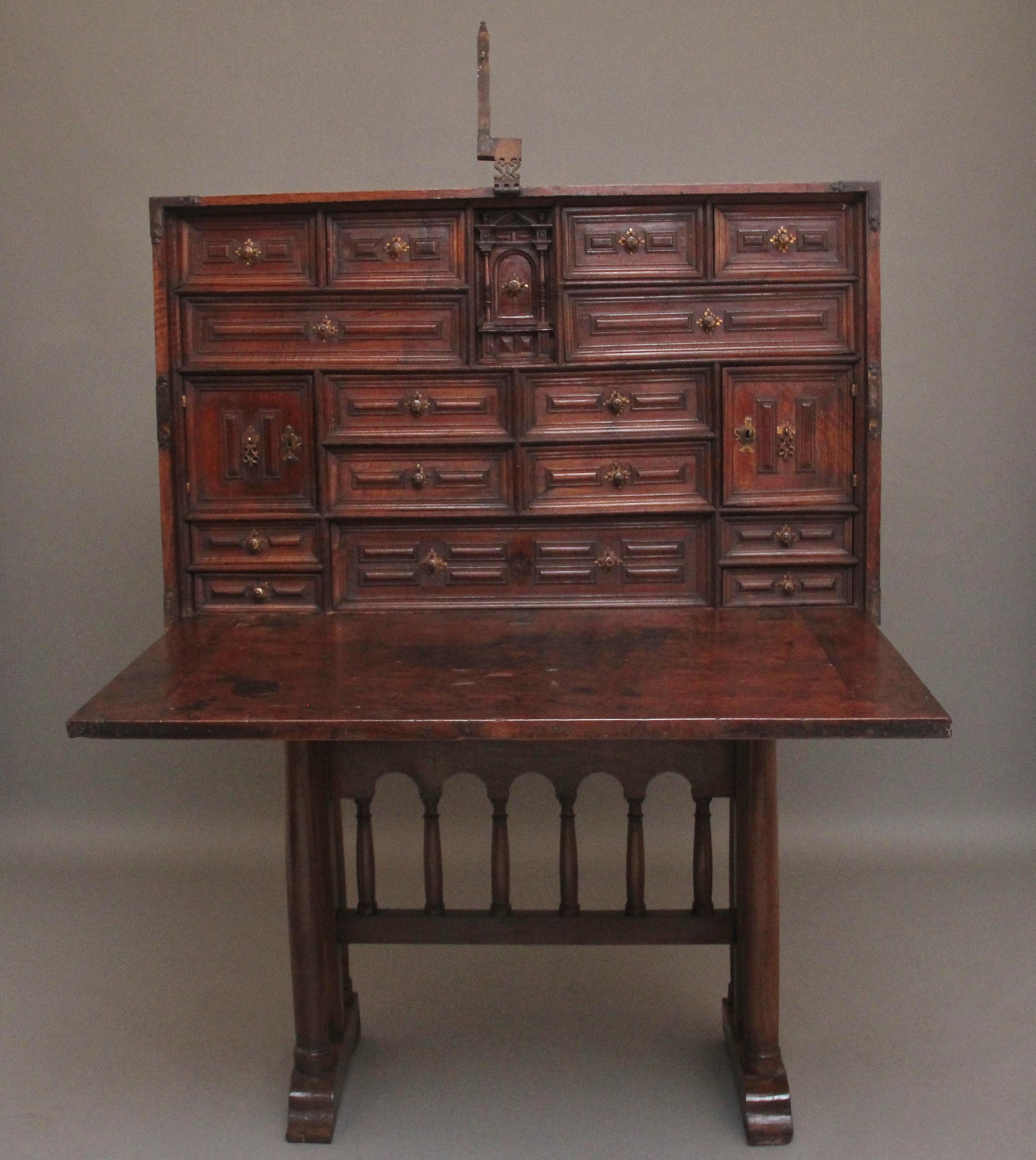 A superb quality 17th Century walnut Vargueno on stand, the rectangular case having the original iron carrying handles either side and strapwork decoration, the front having a shield shaped lock plate at the centre and and engraved lock plates at
