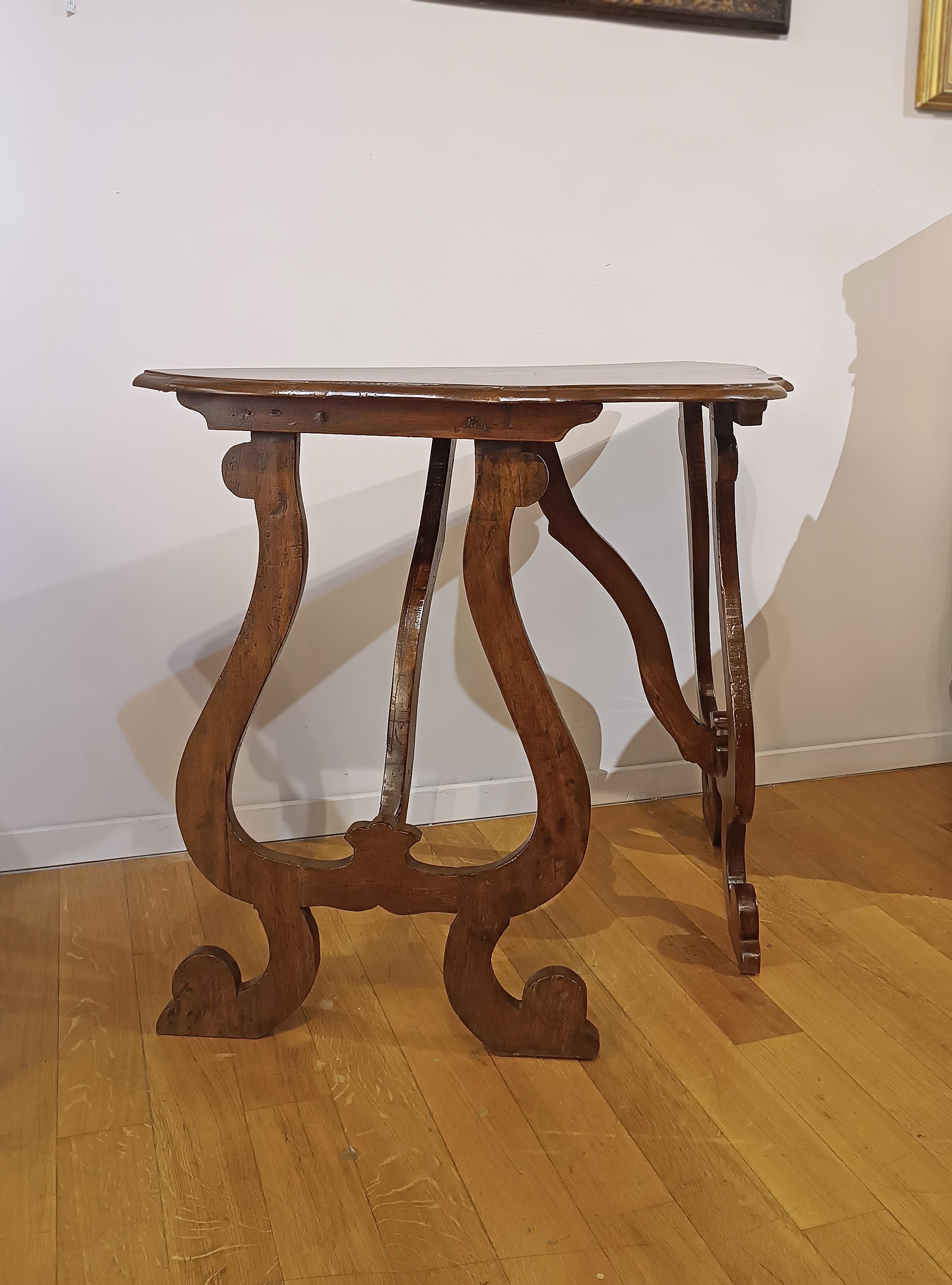 Elegant small wall consolle made of solid walnut. The curved top gives a touch of refinement, while the legs with double lyre slats, typical of Tuscan manufacturing from the Louis XIV period, enhance the classic style. The structure is completed by