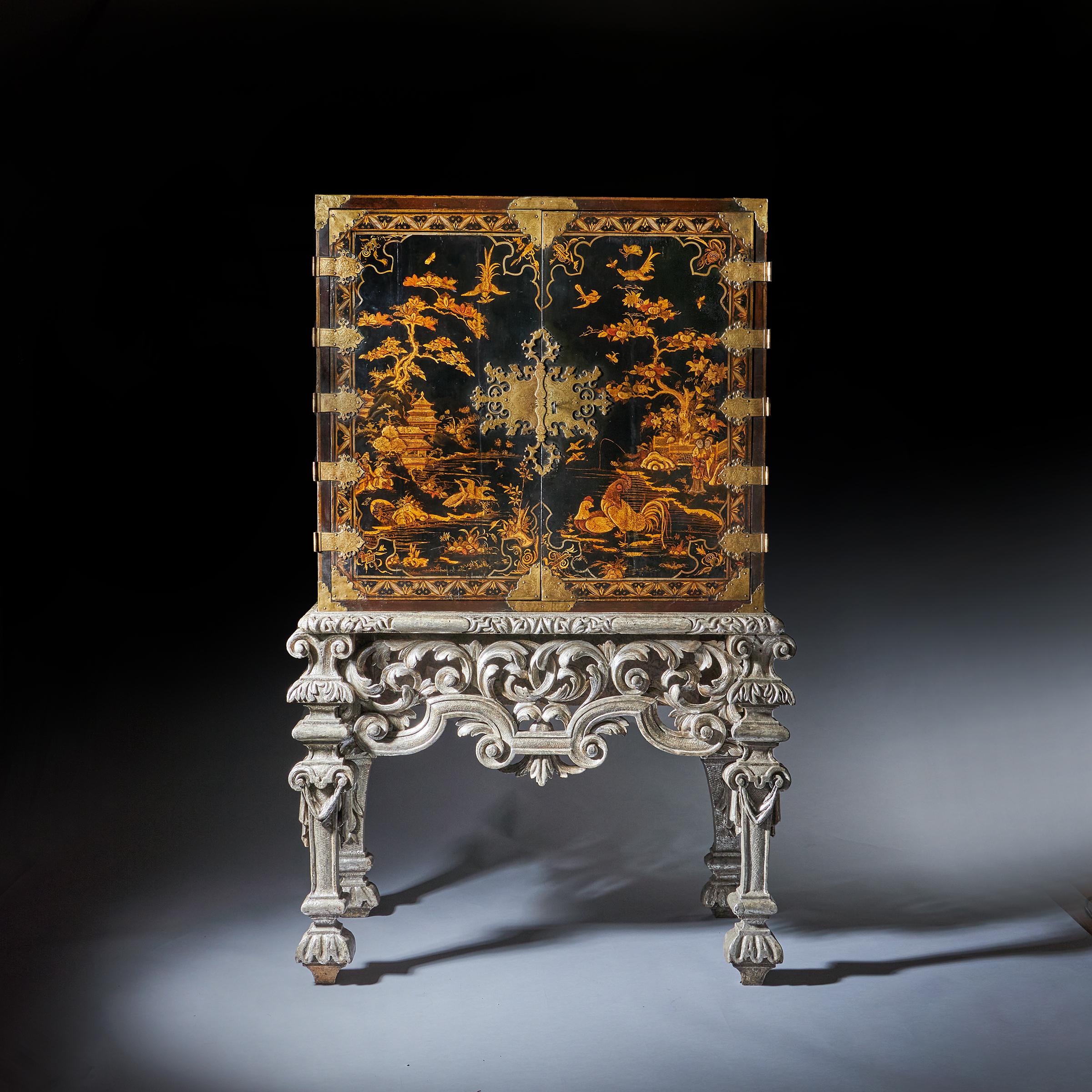 An important and exceptional quality late 17th century William and Mary japanned cabinet on original carved silver gilt stand, C.1690-1700

The upper part, decorated with coastal landscapes depicting homes, figural scenes, fauna and flora with a