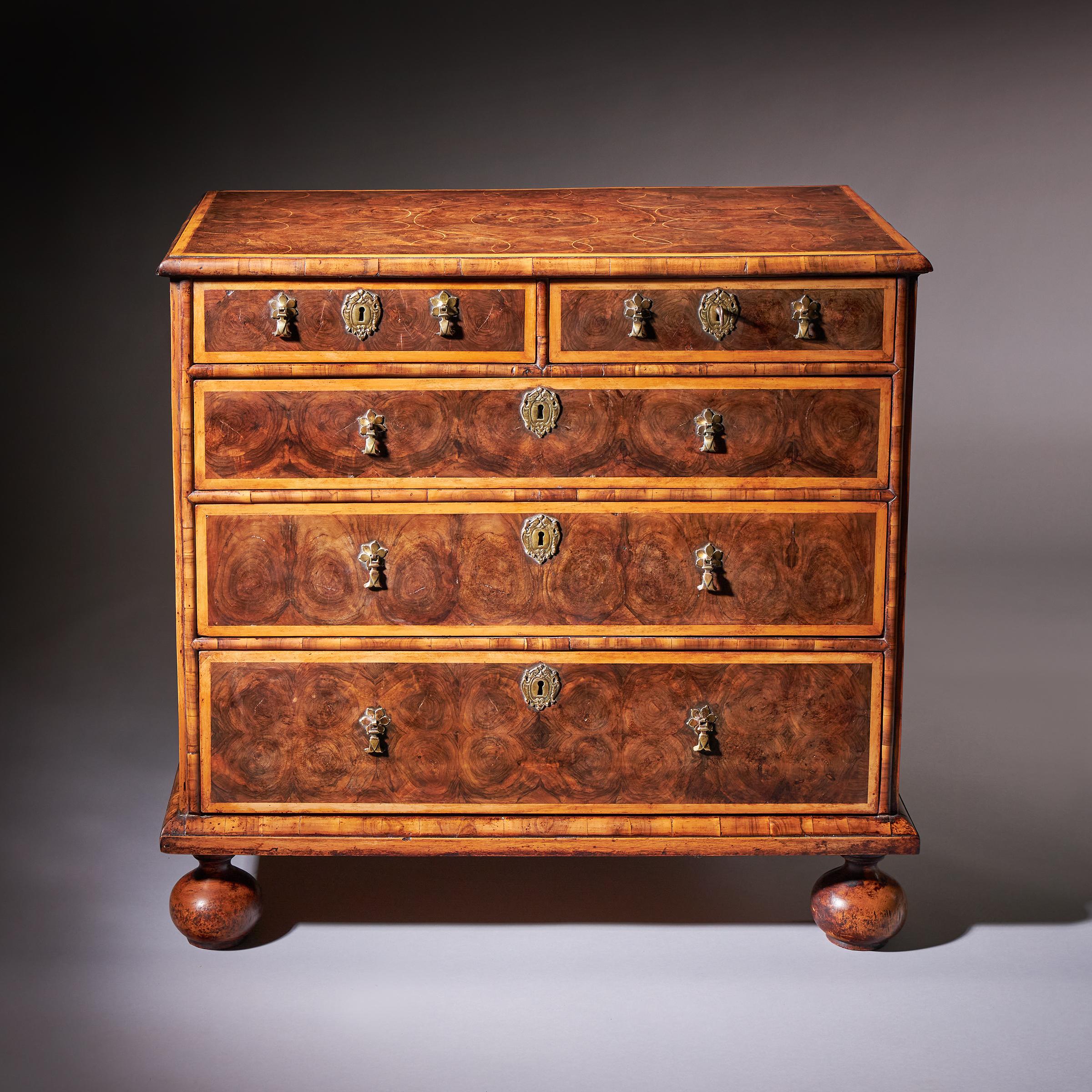 Cette exquise commode d'époque William and Mary, fabriquée à la fin du XVIIe siècle, témoigne d'un savoir-faire artistique exceptionnel, tant au niveau de la forme que des matériaux. Le coffre est construit en bois d'olivier richement patiné et