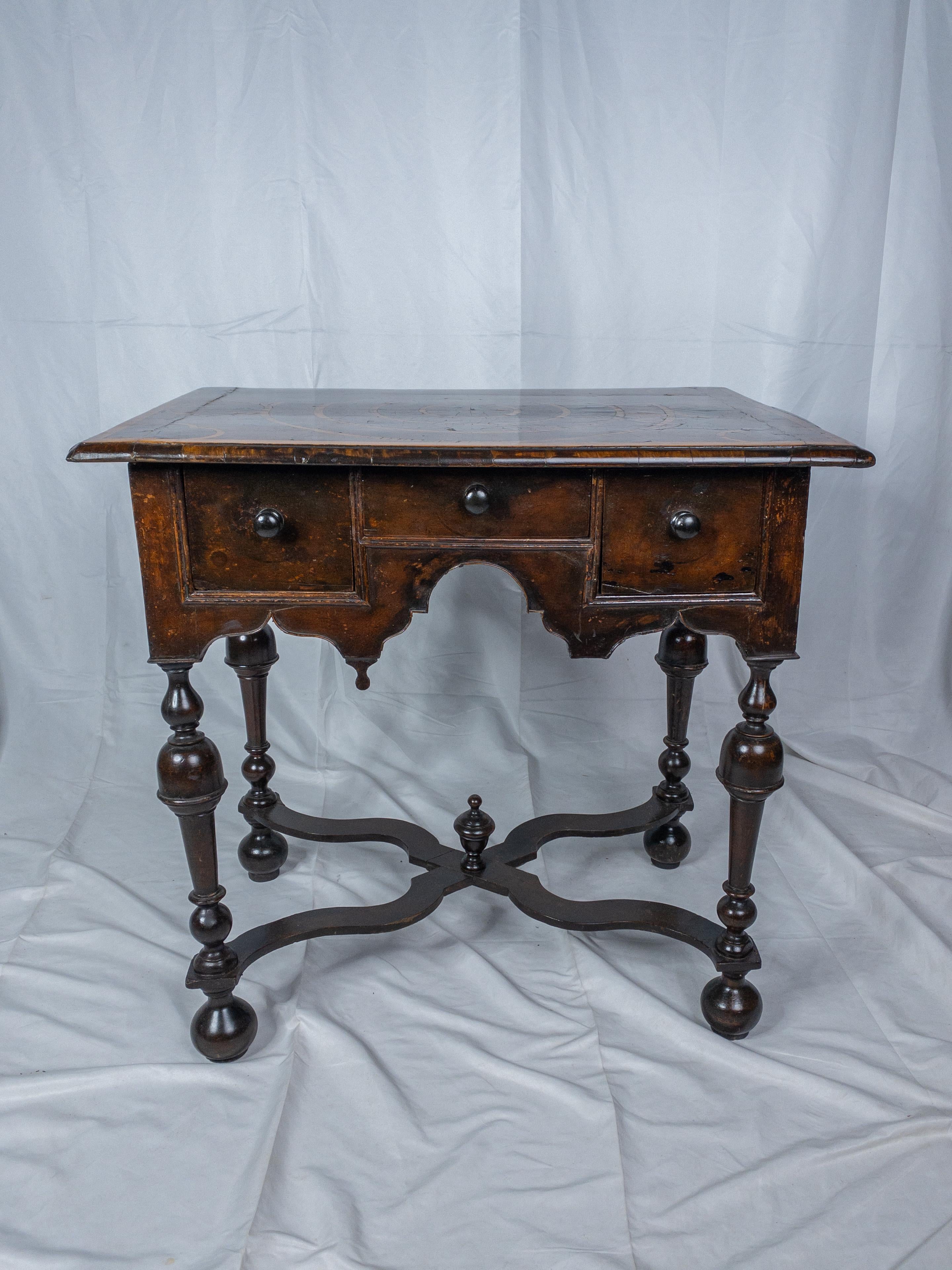 The 17th Century William and Mary Oyster Veneered Walnut Dressing Table stands as a testament to the exquisite craftsmanship and design sensibilities of the period. Its tabletop is adorned with oyster veneer, a luxurious touch that adds depth and
