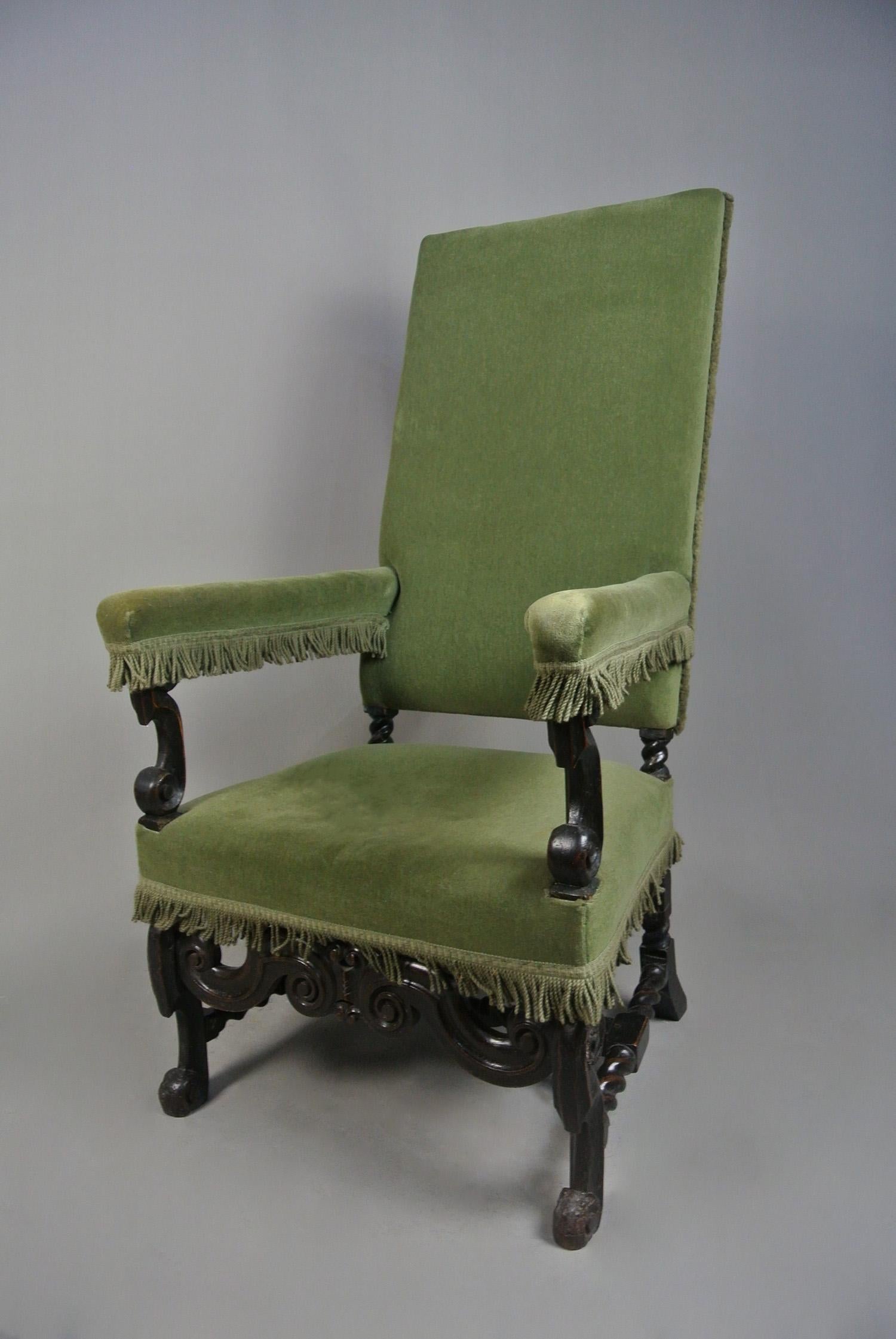 A beautifully shaped William and Mary oak armchair with well carved horse-bone legs and arm supports, scrolled feet and handsomely carved front stretcher with S scrolls and geometric motif.  The tall upholstered back over spiral turned legs and