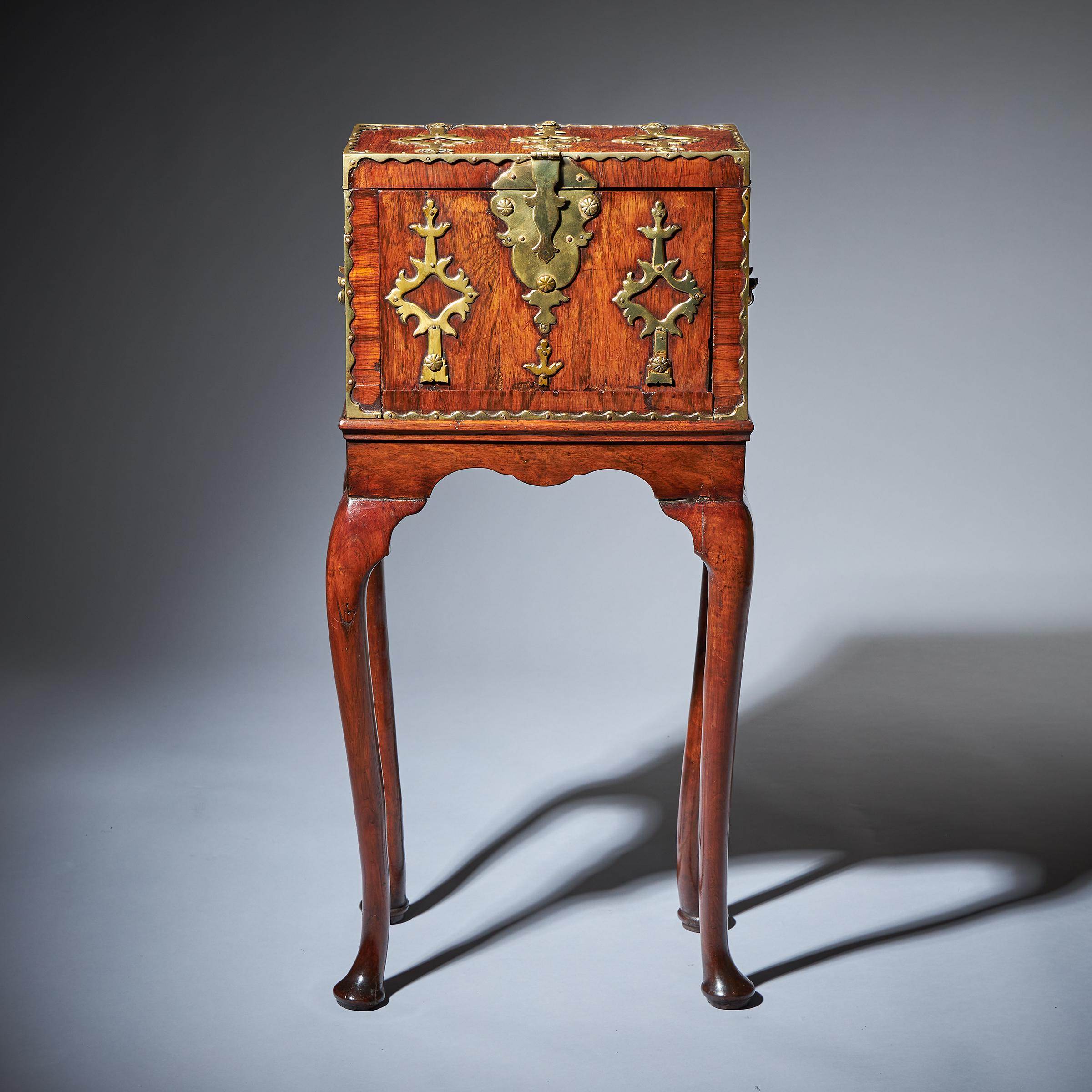 The unique 17th-century William and Mary rosewood coffre forte, circa 1690, raised on George I walnut stand, circa 1720. 

The rosewood veneered exterior is entirely decorated in gilt brass straps. Once the lid is opened you can open the gilt