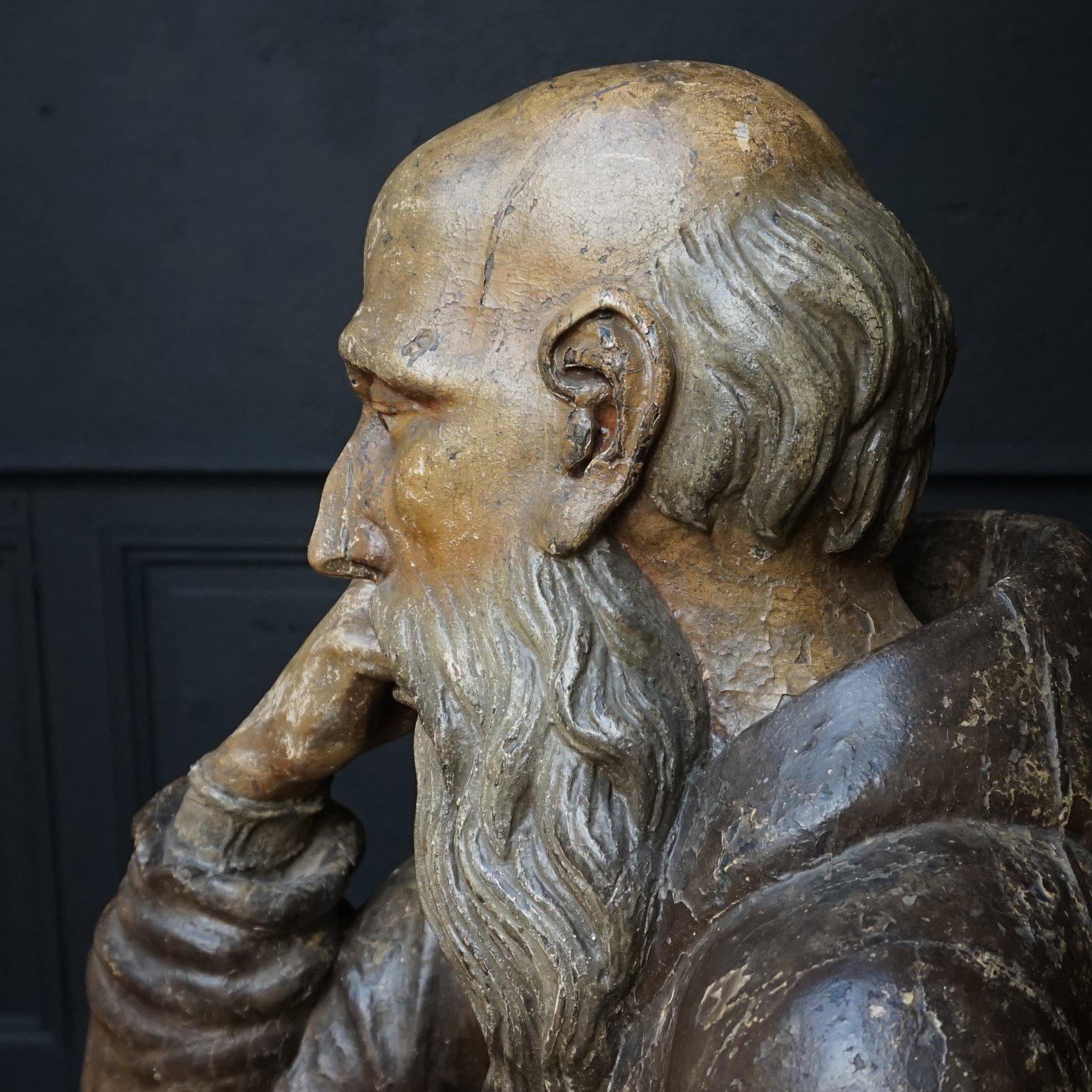 Solid wooden lifesize contemplating and begging Franciscan church statue sitting and leaning on his elbow. 
The table, chair and bible pictured with him are optional 

The Franciscans are a group of related mendicant religious orders within the