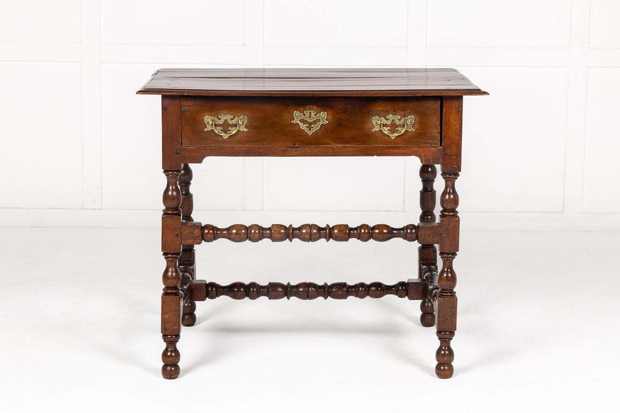 17th Century solid yew wood side table having a plank top with moulded edges. A single frieze drawer with brass handles and escutcheons. Raised on very nice, well turned legs and the front legs have an unusual feature of a high, turned stretcher. A