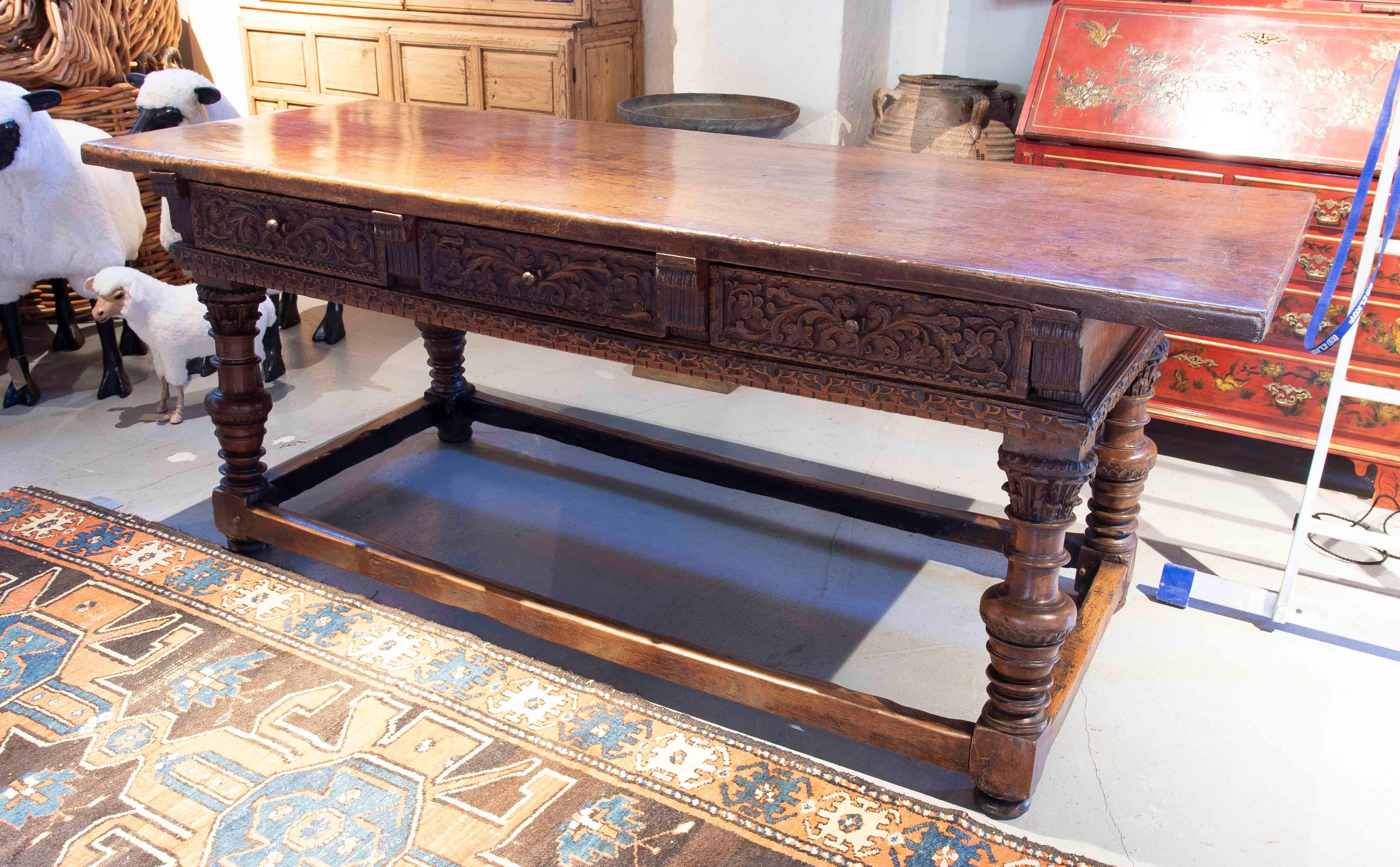 Majestic antique Burgalesa table (Northern Spain) made of solid wood, highlighted by its exquisite handcrafted carving work on the front drawers, which present elaborate floral and geometric motifs. This piece combines robustness with timeless