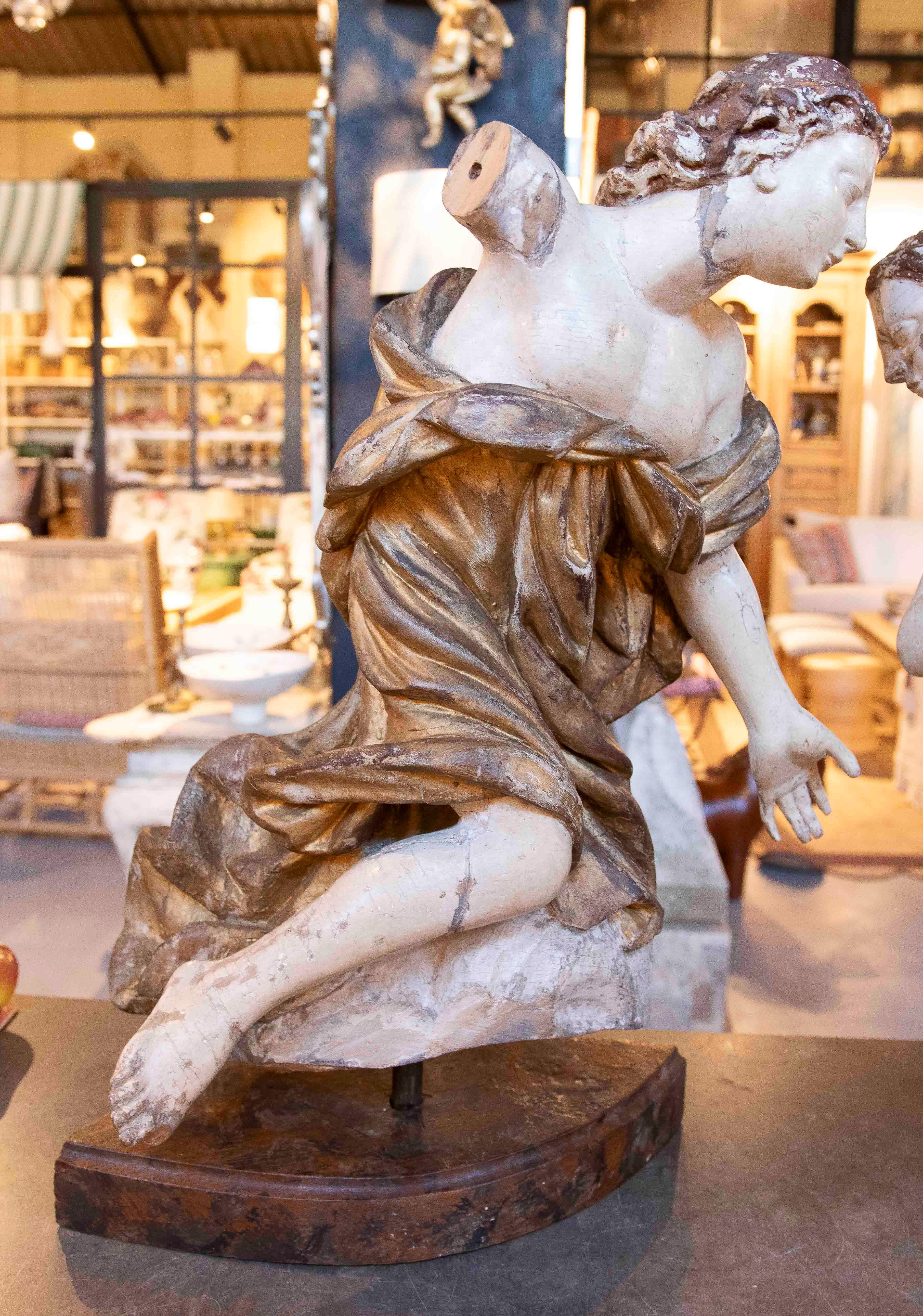 Exquise paire d'anges antiques sculptés en bois polychrome, représentant des figures féminines en mouvement, avec des postures dynamiques et expressives qui transmettent élégance et grâce. Chaque figure présente des détails soigneusement élaborés,