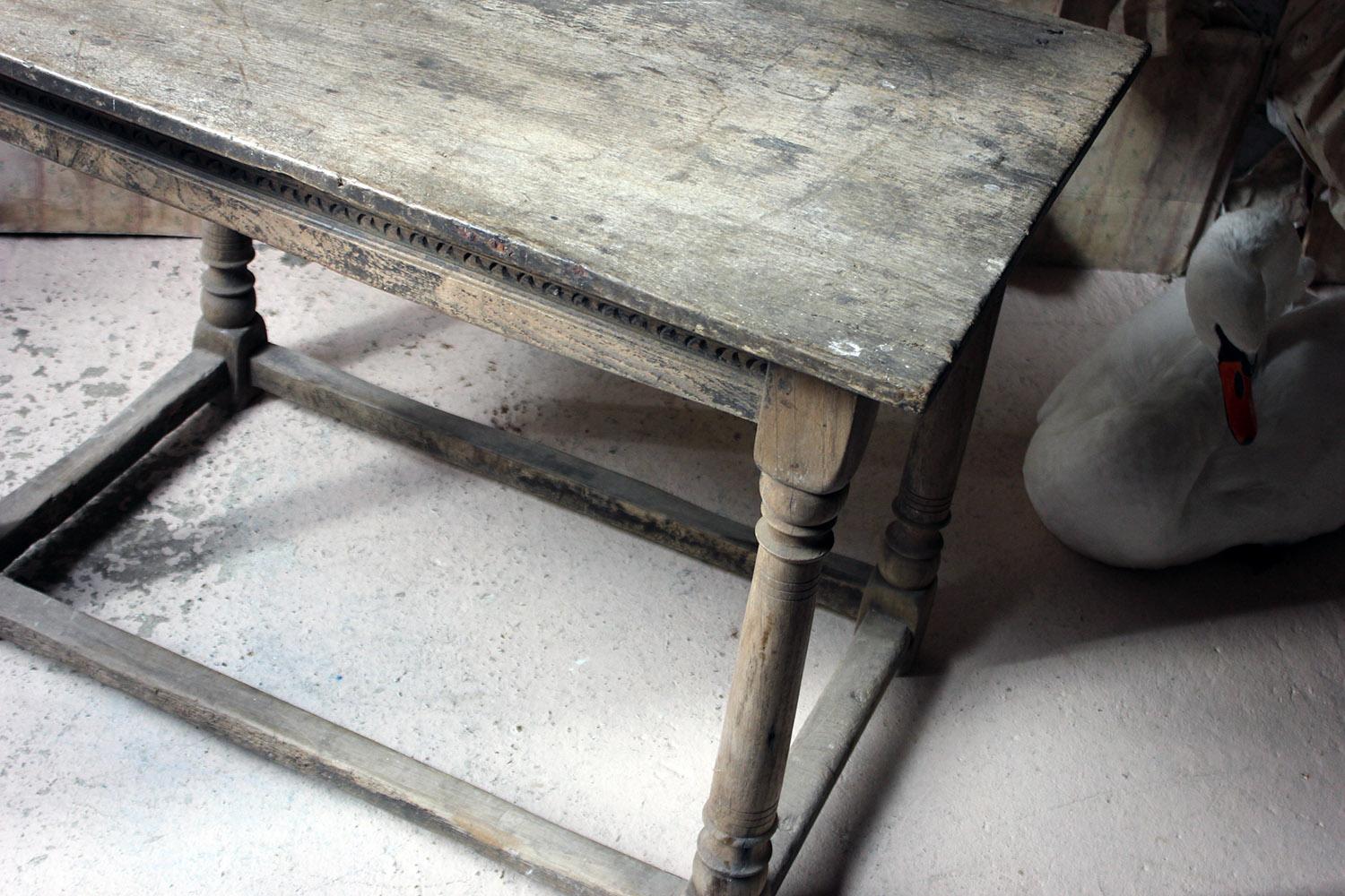 The seventeenth century oak side table having a three-plank top with chip carved frieze above gun barrel and incised turned legs to block feet and conforming stretchers, the whole in beautifully dry aged condition, surviving from Charles II period