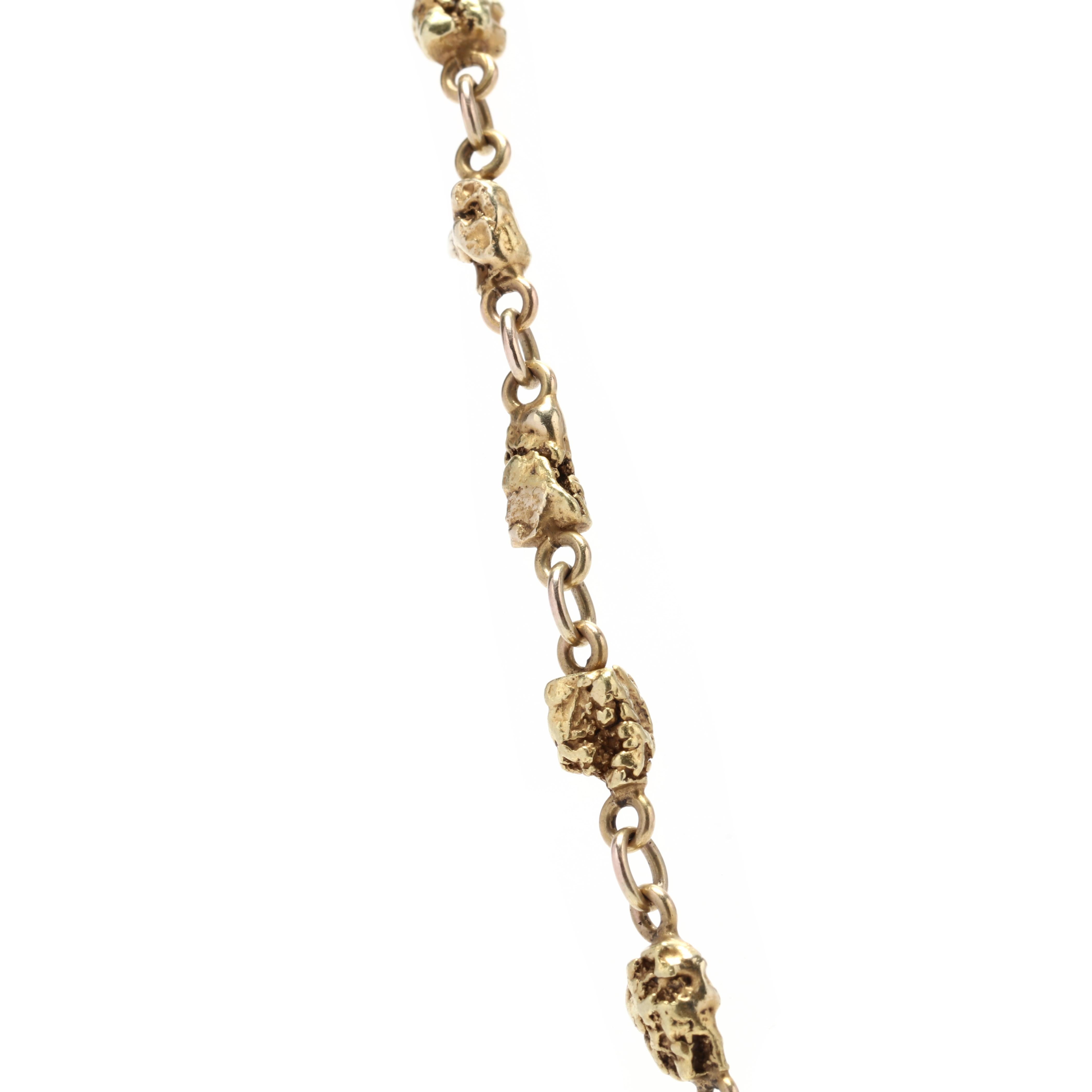 A handmade 18 and 14 karat yellow gold nugget chain. This chain features 14 karat gold nuggets linked together in the center with an 18 karat gold rolo chain on either side with a spring ring clasp.



Length: 16.25 in.



Width: 5.5 mm



Weight: